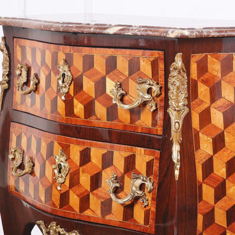 A French Louis XV style bombe commode with dramatic parquetry veneering in contrasting fruitwood, mahogany, and satin birch. Original fine gilt bronze mounts and marble top. Two drawers, each with ornate Rococo handles and ornate key
