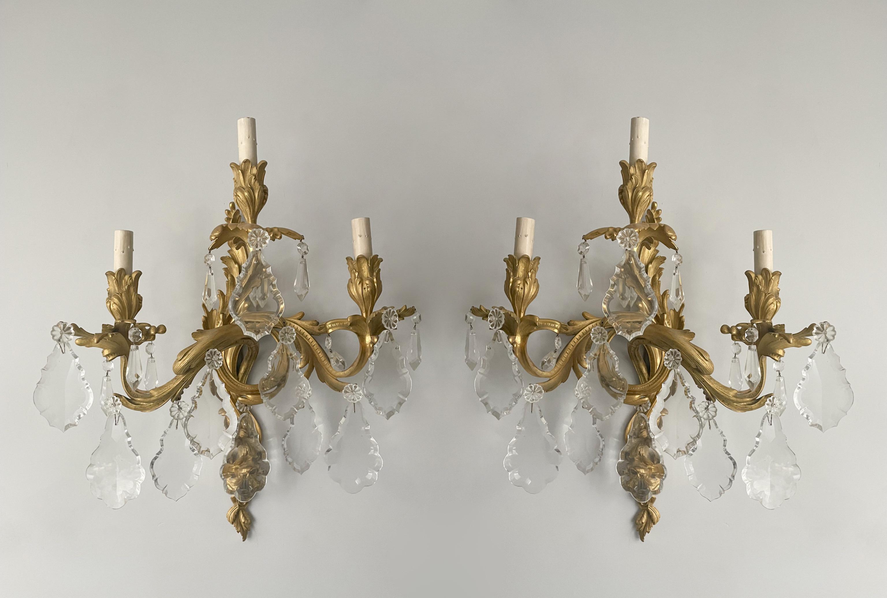 Gorgeous, French 1940s pair of bronze and crystal sconces in the Louis XV style.

Each sconce features a bronze-doré frame with fine ormolu details and crystal pendants. 

The sconces are wired and in working condition, each requires 3