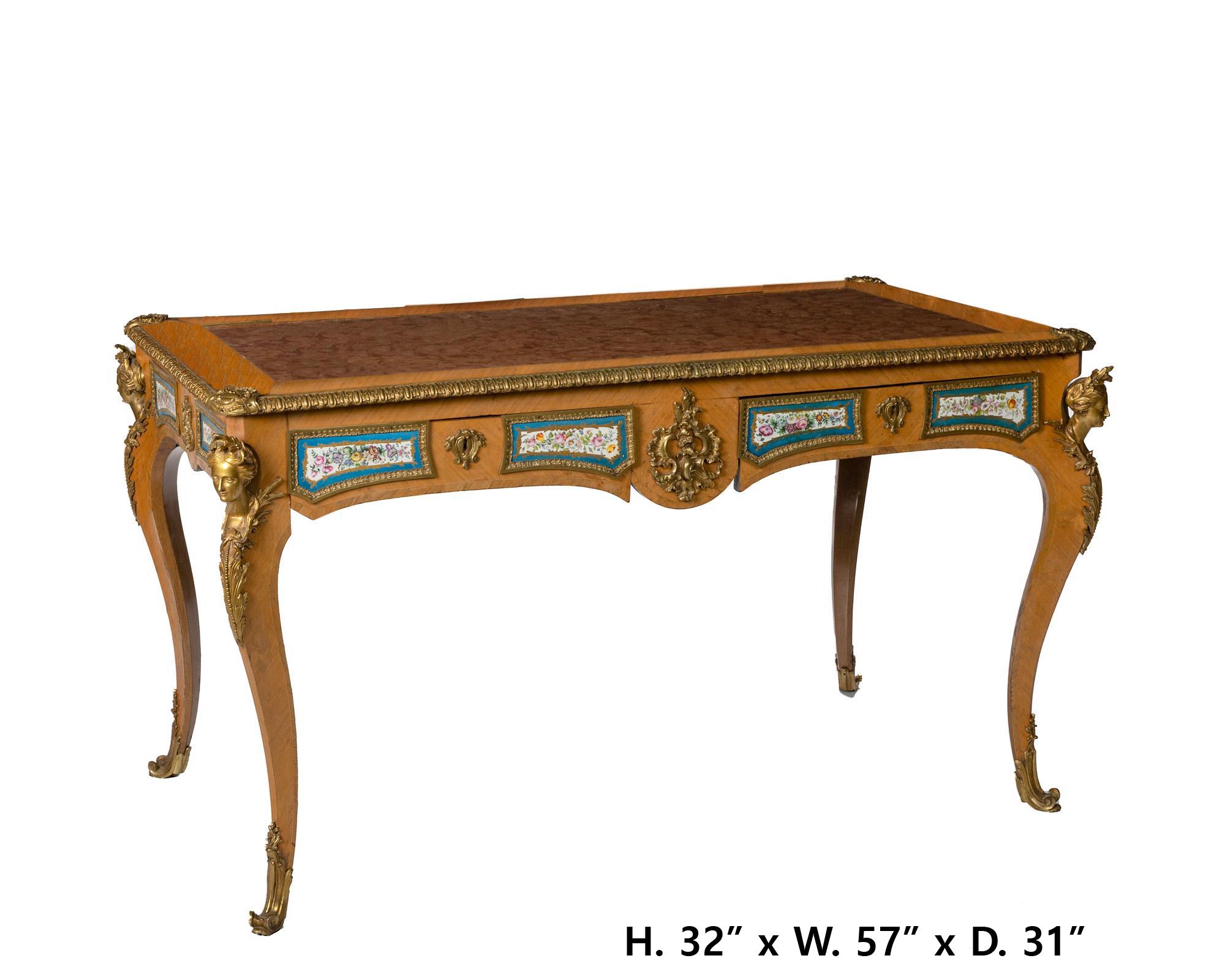 Late 19 century French Louis XV stylekingwood veneered bureau plat with inset marble top over a gilt-bronze mounted apron with inset Sevres porcelain plaques and two frieze drawers raised on four cabriole legs with figural masks and sabots to the