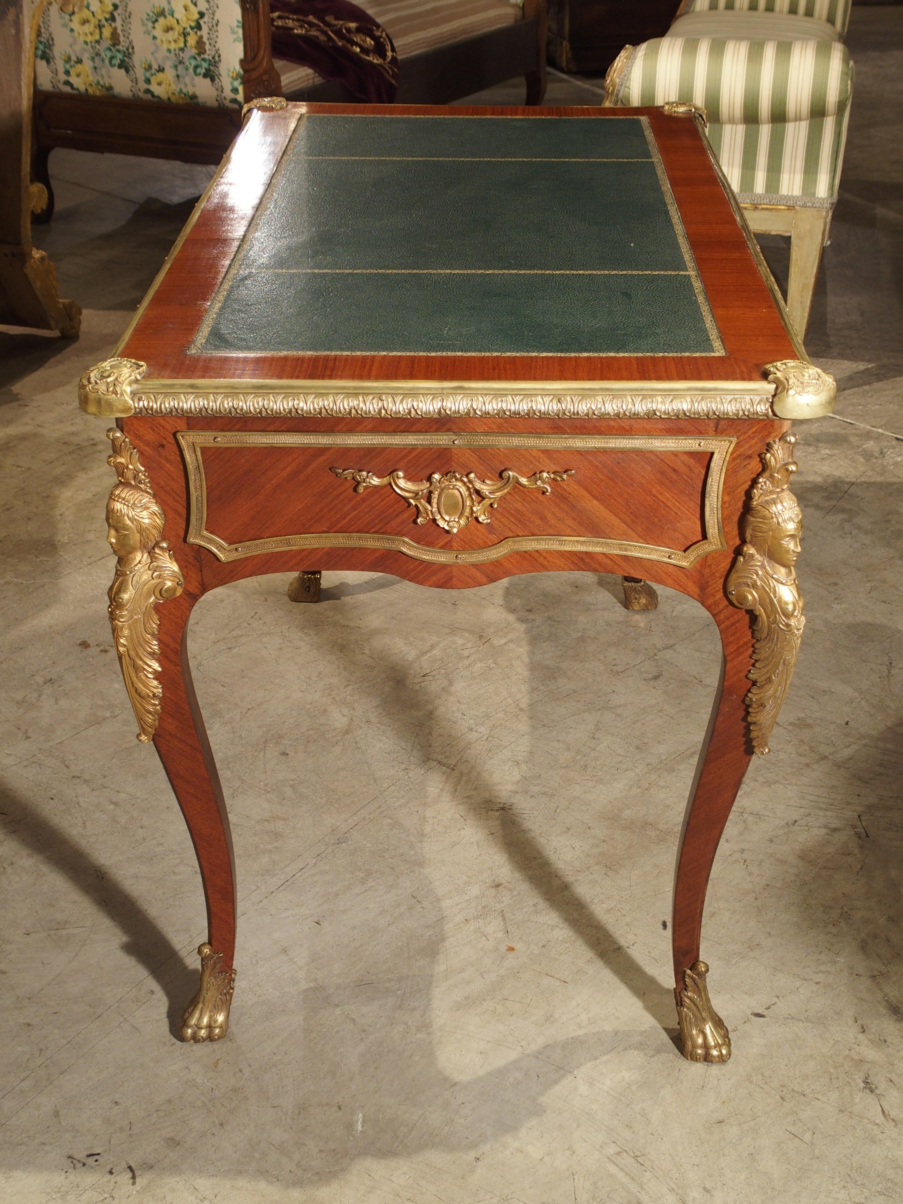 This Louis XV style Bureau plat writing desk from France will be perfect in any room. It has veneered exotic wood, elegant bronze mounts and a gilt embossed leather top. There is a single drawer running the length of the leather top on one side,