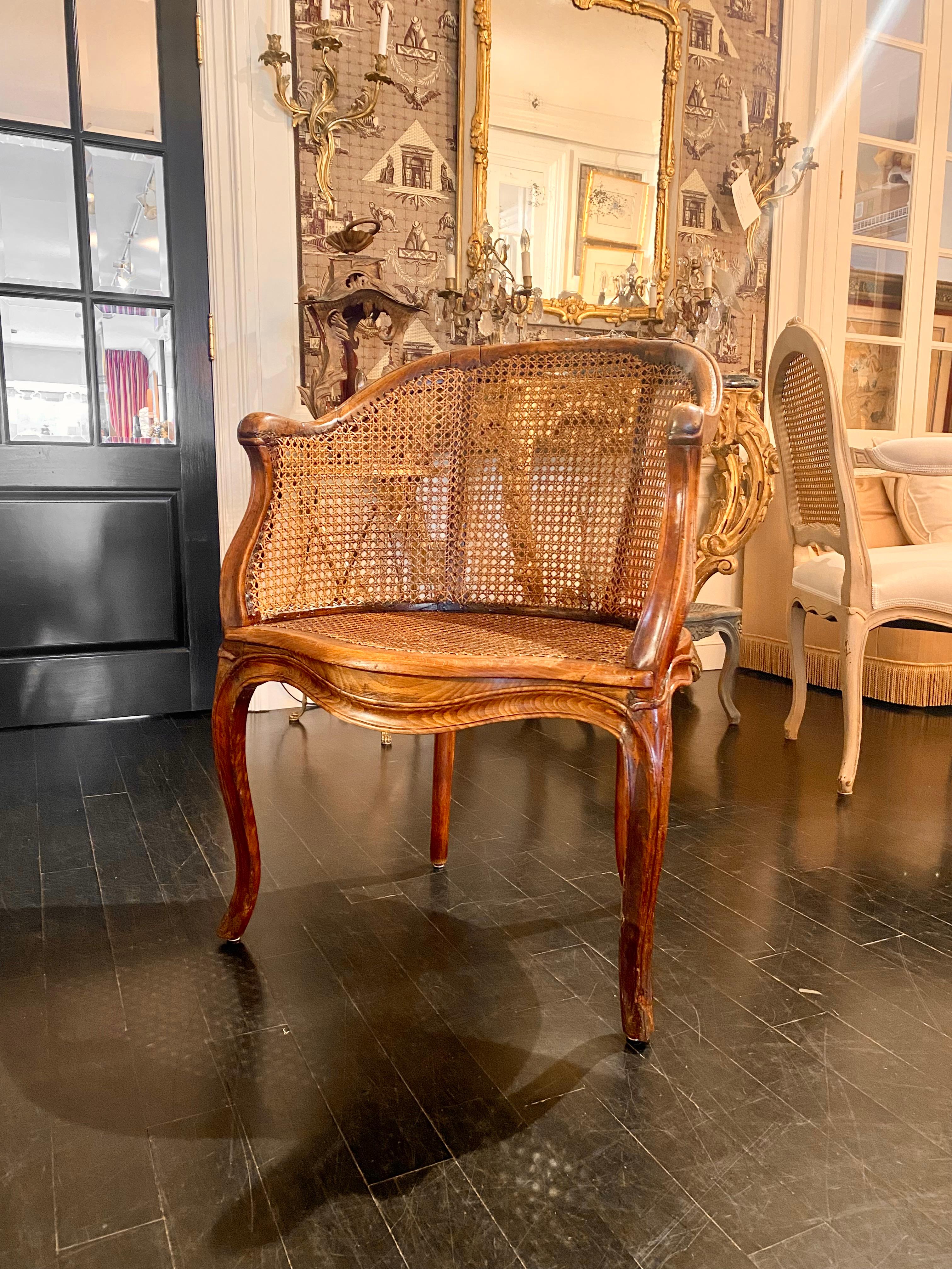 Rare early 19th century caned Louis XV bergère armchair in very good condition featuring graceful curves and hand carved. The graceful walnut frame is complimented with caning on all sides which gives a sense of lightness to piece. Cabriole legs