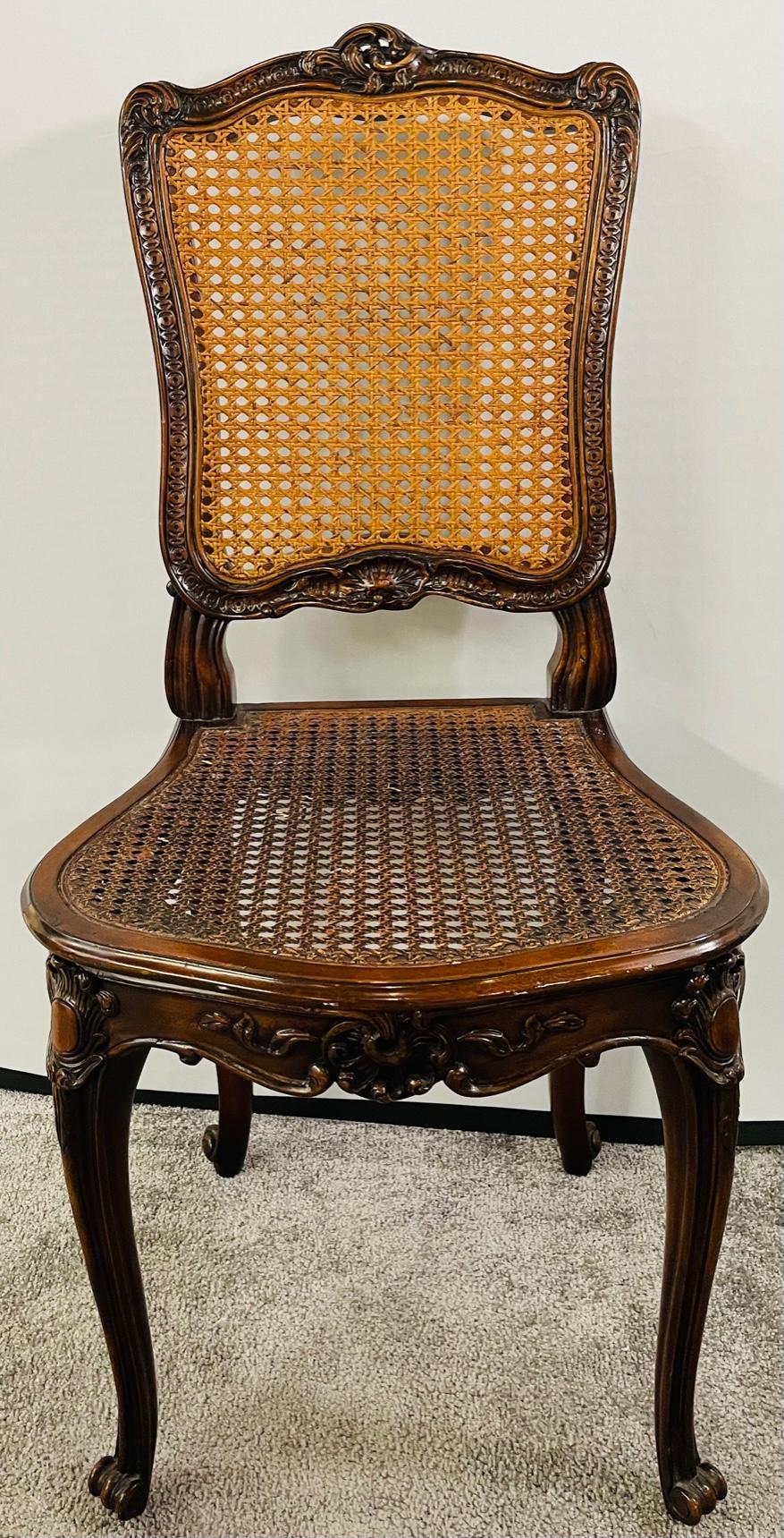 A set of 4 French Louis XV carved walnut side chairs featuring a caned back and seat , the former in light tone, the latter in darker tone. The chairs are hand carved of quality walnut wood in curvy design with flowers and scroll design embellishing