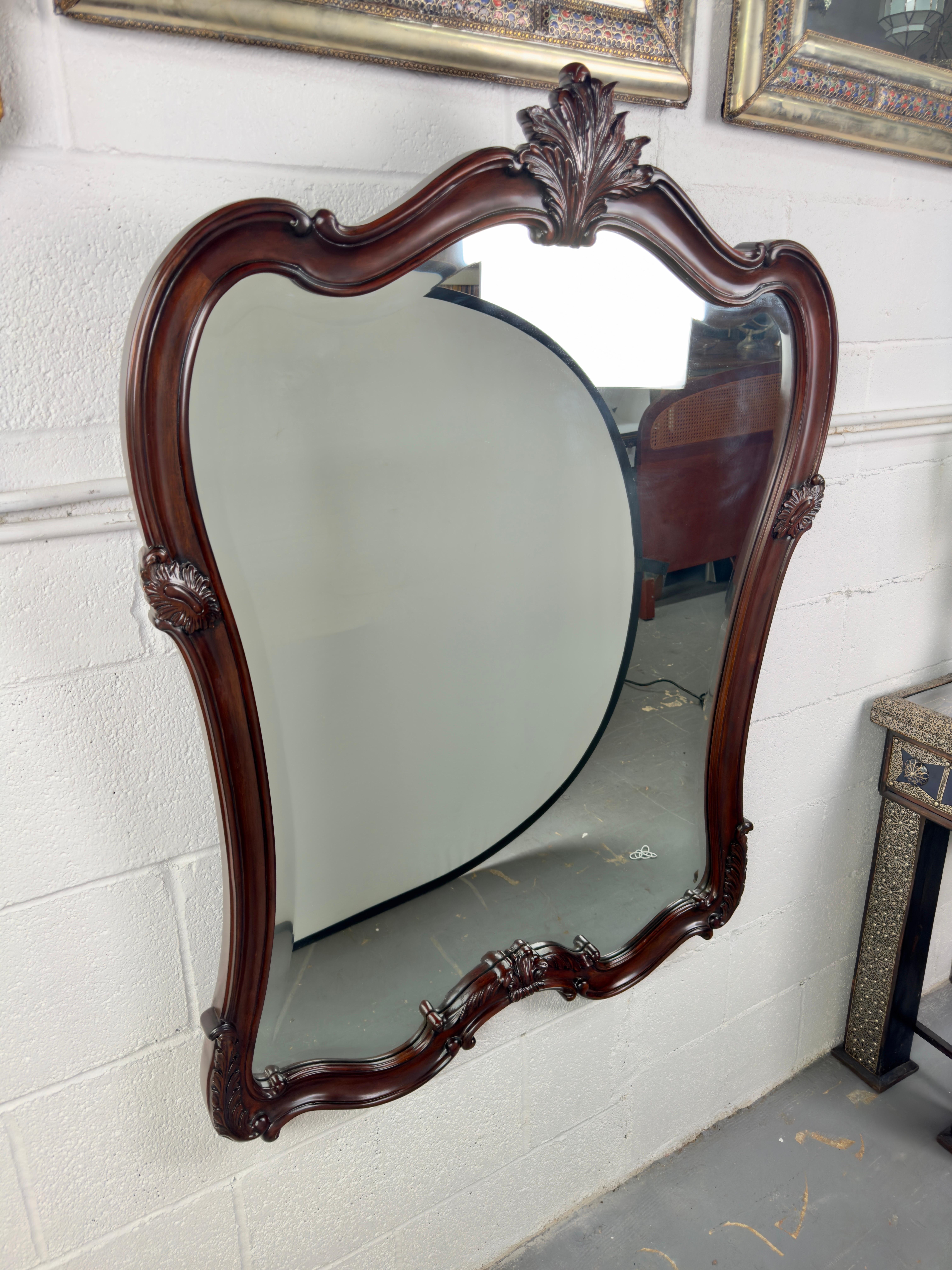 An  exquisite Louis XV style cherry wood  frame mirror. A relic from the late 20th century, this vintage masterpiece exudes opulence and sophistication.
Crafted with meticulous attention to detail, the mirror boasts a cherry wood  frame adorned with