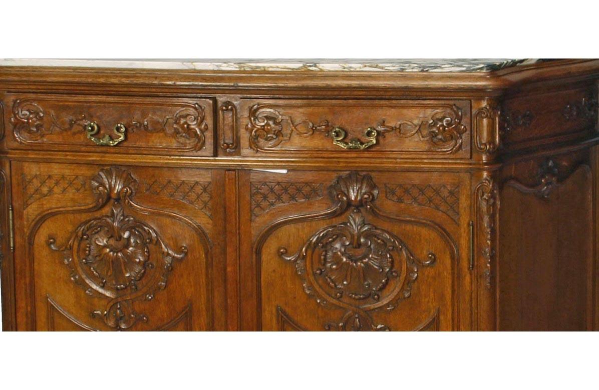 Finely carved 19th century Louis XV style carved oak two-door cabinet. Inset serpentine marble top over two foliate carved short drawers with bronze mounts above two delicately carved doors with an acanthus and shell motif, supported by four
