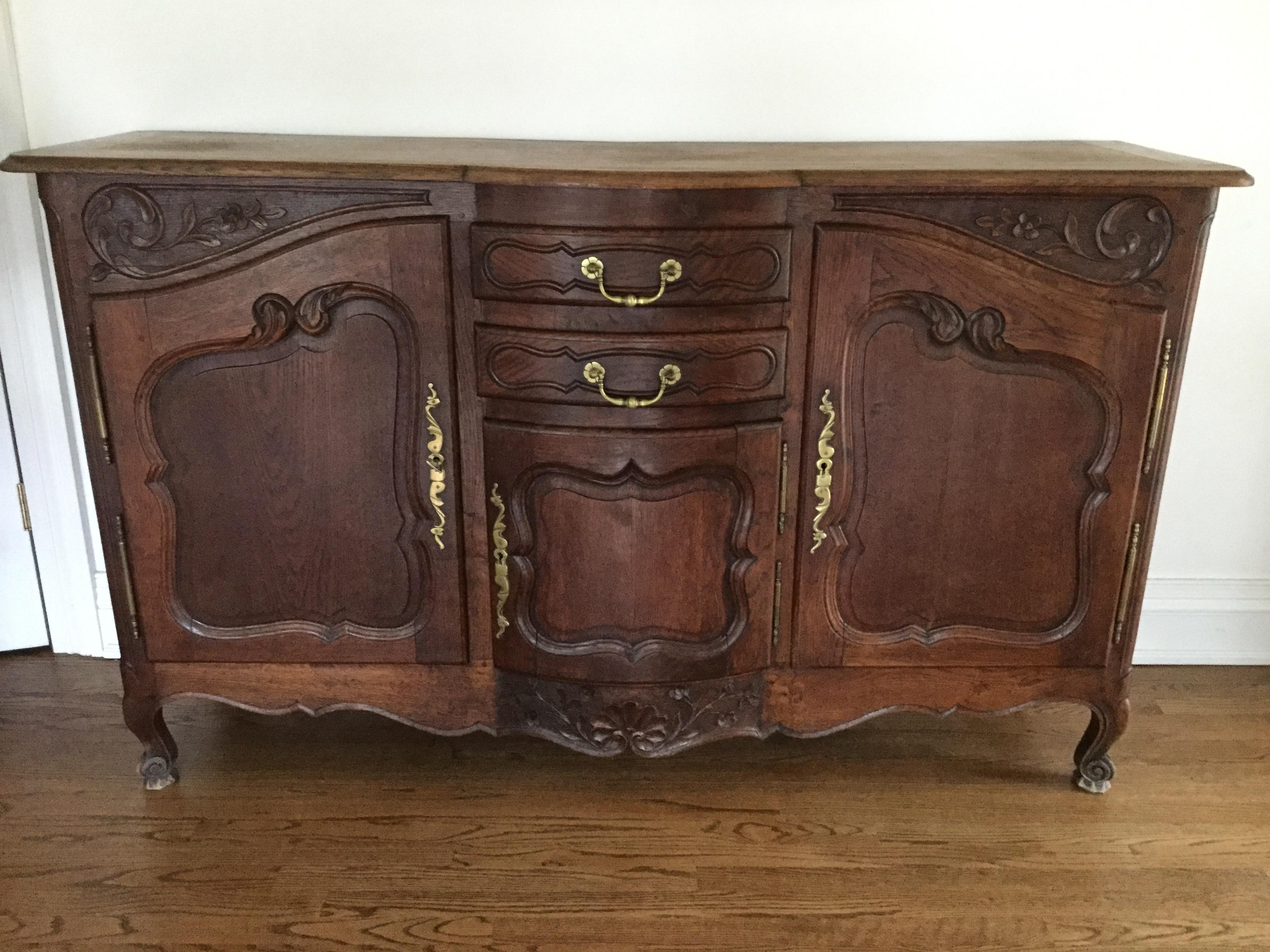 Elegant and practical French sideboard. This Louis XV-style piece features 2 side doors and a middle bombe door with 2 drawers. Each door contains a raised panel for greater quality and is enhanced with elegant carvings depicting floral motifs and