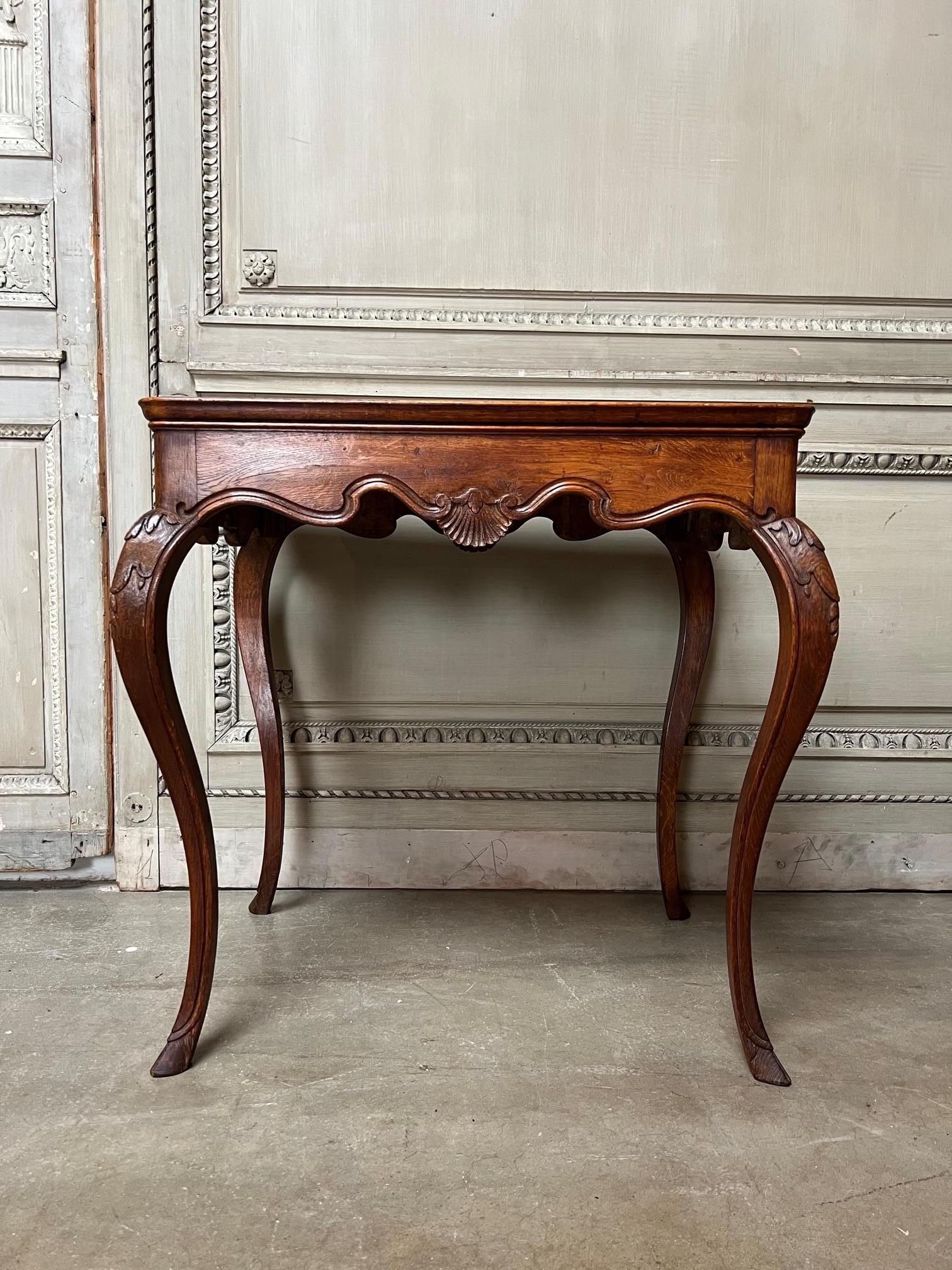 A fine French Louis XV style carved oak table with robust cabriole legs and carved apron. It has a lovely old patina dating from the mid 19th century. The table has a very special and unique top of a recessed parquetry design of 35 different marble