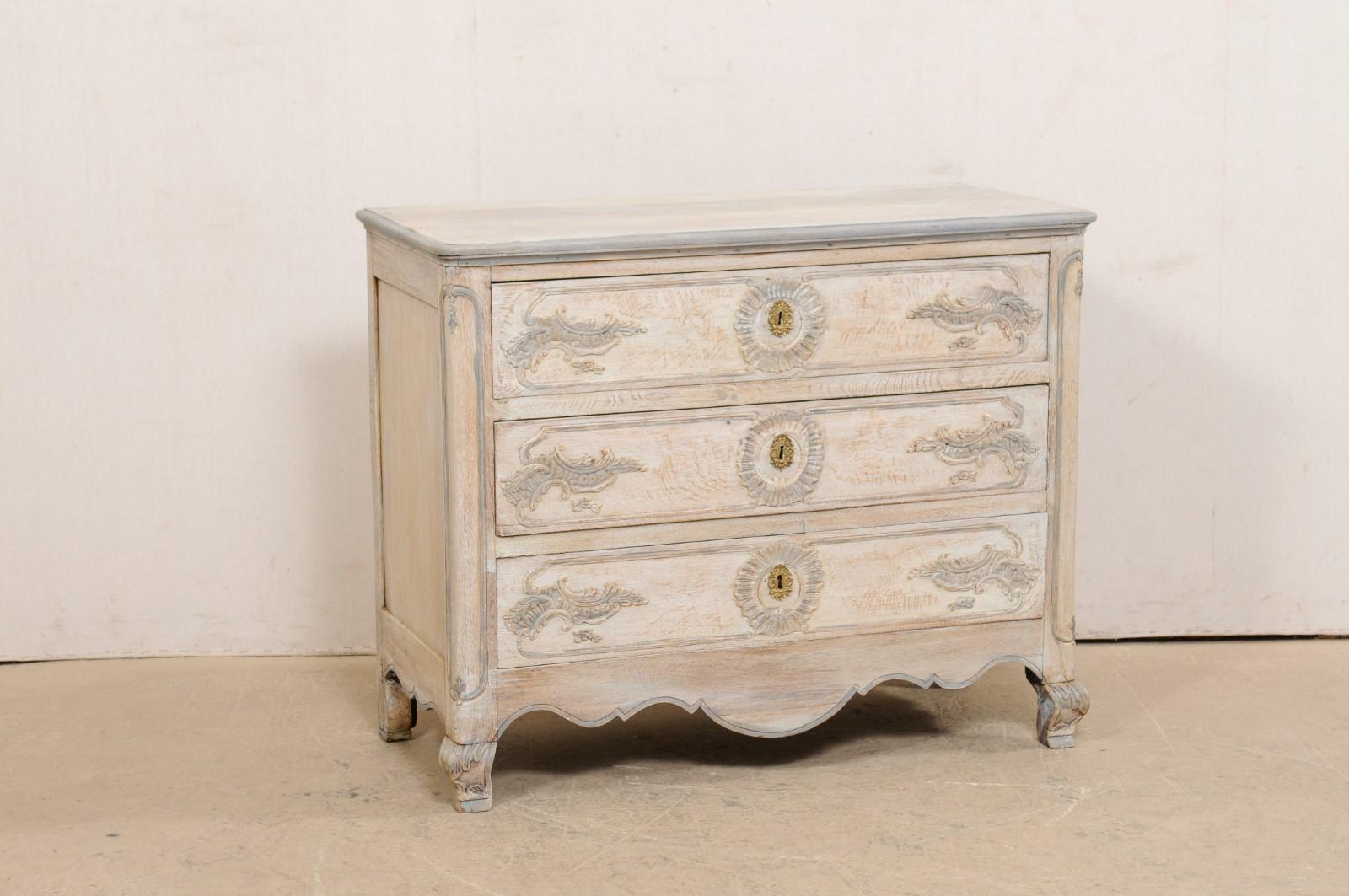 A French Louis XV style carved and painted chest from the late 19th century. This antique commode from France features three dove-tailed and graduated drawers, which have been carved in the decorative vocabulary typical of the Louis XV style,