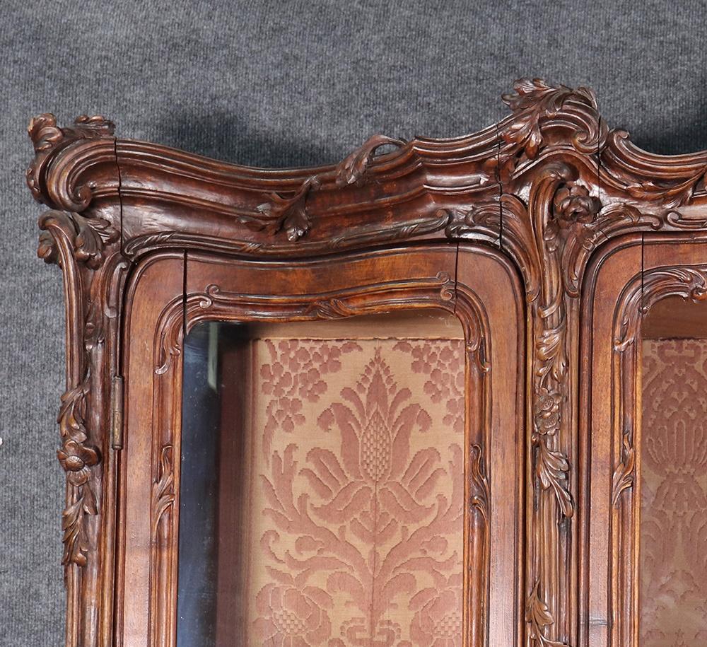 French Louis XV style carved walnut breakfront. Dating to the 1860s era and made in Paris, this incredible cabinet has no equal. The carved frame is fitted with beautiful bowed or serpentine glass and the glass shelves are adjustable and the back is