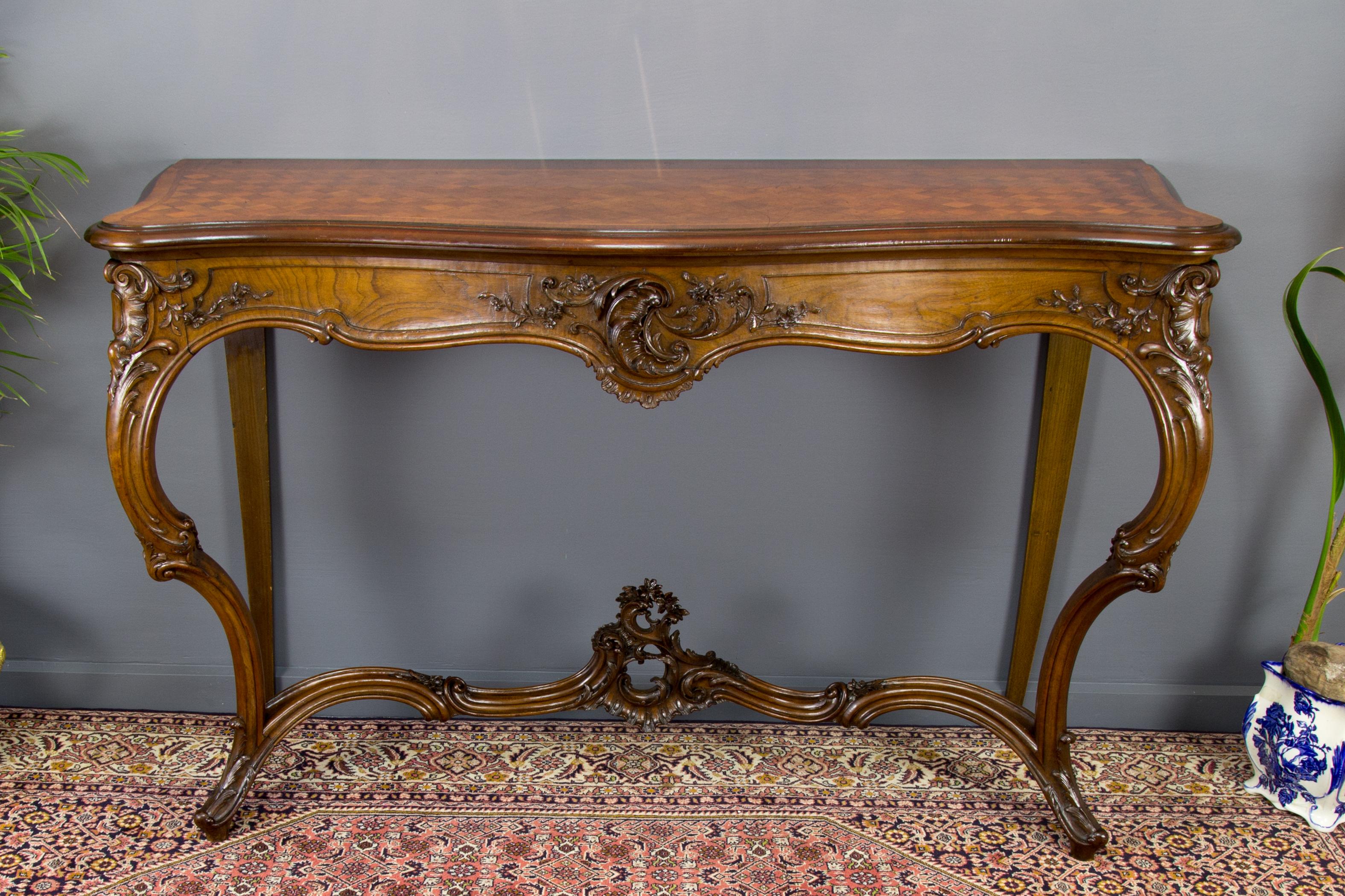 Exquisite beautifully carved walnut console with a crossbanded parquetry top. This large French Louis XV style console has finely carved rocaille, foliate and floral motifs. The well-molded front standing on finely carved Cabriole legs joined by a