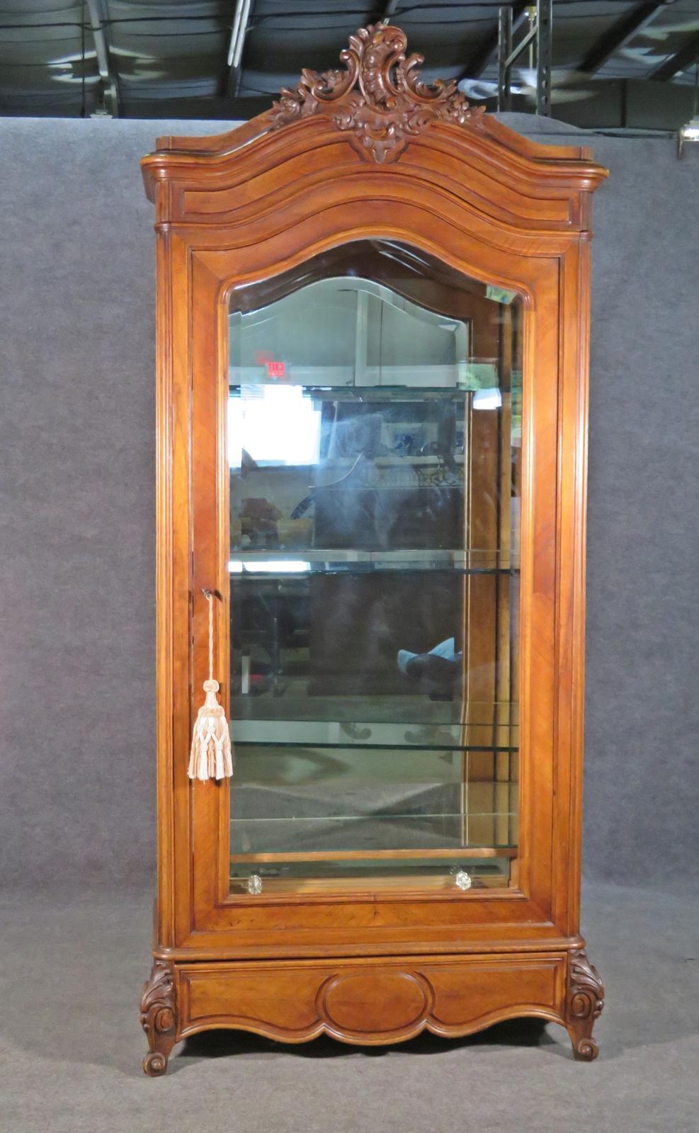 Description
Wood frame. Beveled glass door. Mirrored back, bottom shelf and drawer front. 3 glass shelves.1 dovetailed drawer. Lighted. Carved. 92 1/2