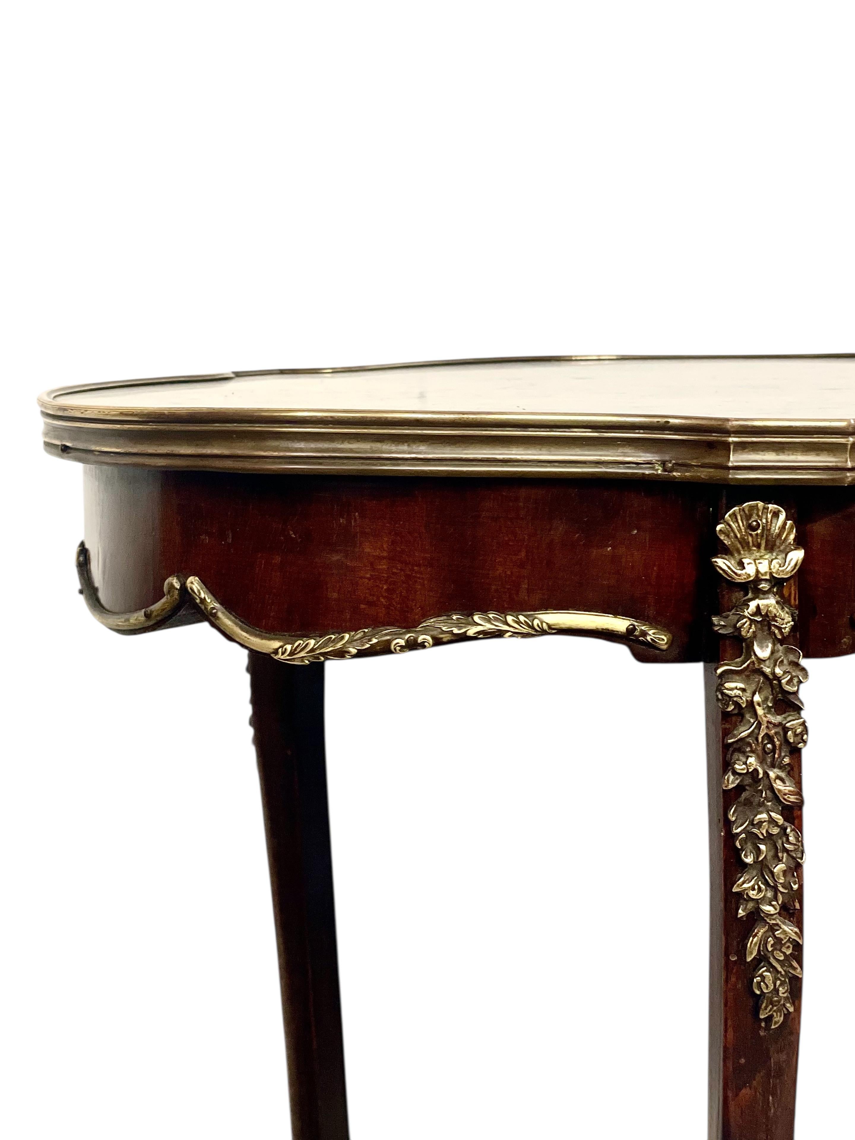 Questo squisito tavolino francese in stile Luigi XV, risalente alla fine del XIX secolo, mostra una raffinata lavorazione artigianale e proporzioni aggraziate. Il piano sagomato è costituito da una lastra di marmo bianco circondata da un'elegante
