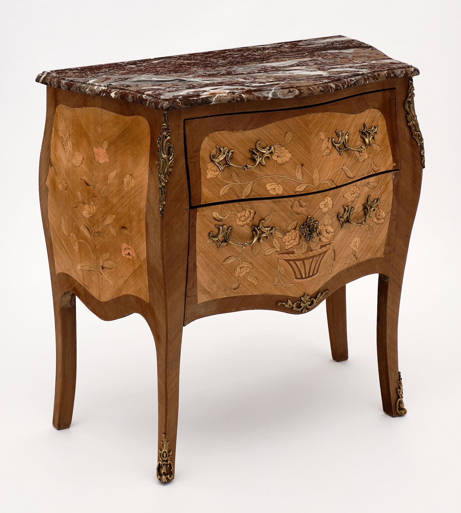 French Louis XV style chest with rouge Royal marble top and serpentine shape. This piece features rosewood and tinted rosewood in a floral marquetry throughout. The rogue royal marble top has beautiful color and veining. The finely cast gilt bronze