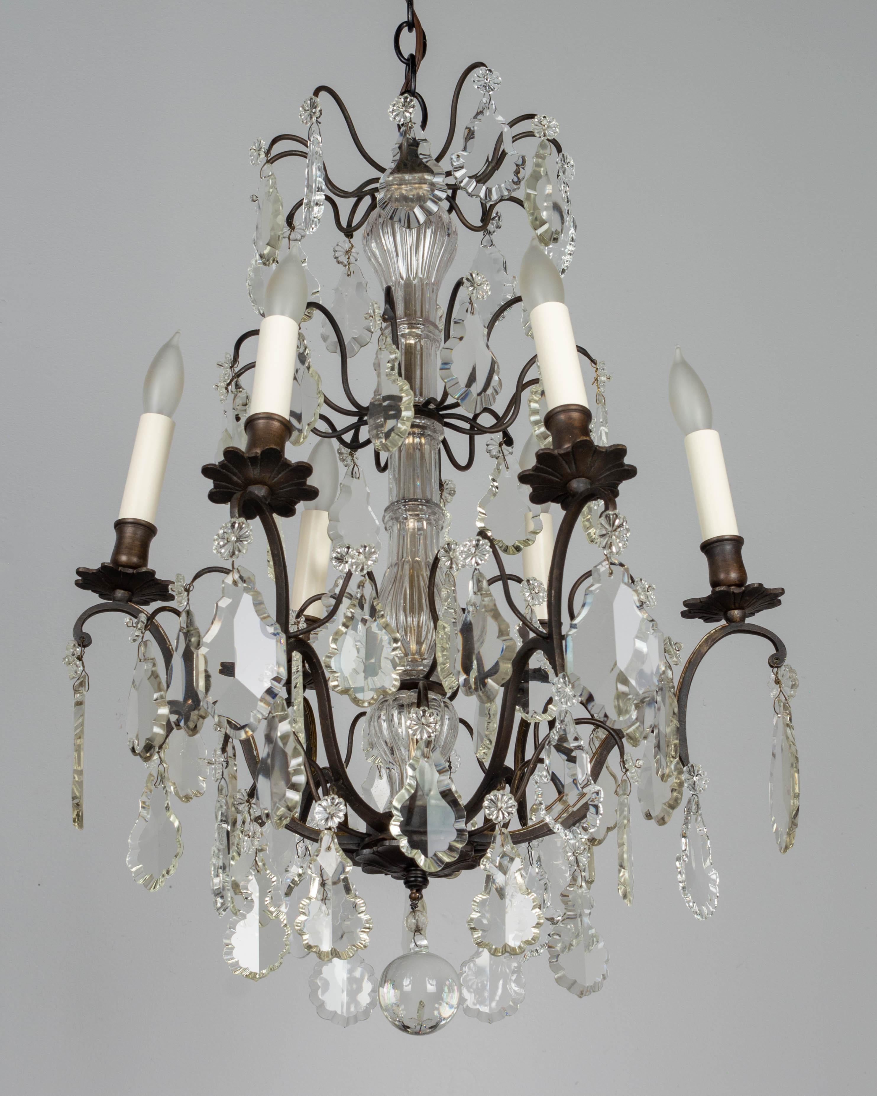 A French Louis XV style six-light chandelier with an assortment of crystal prisms, columns and rosettes. Brass frame with dark bronze patina. In working condition with wiring as found. New candle covers. Please refer to photos for more details.
 