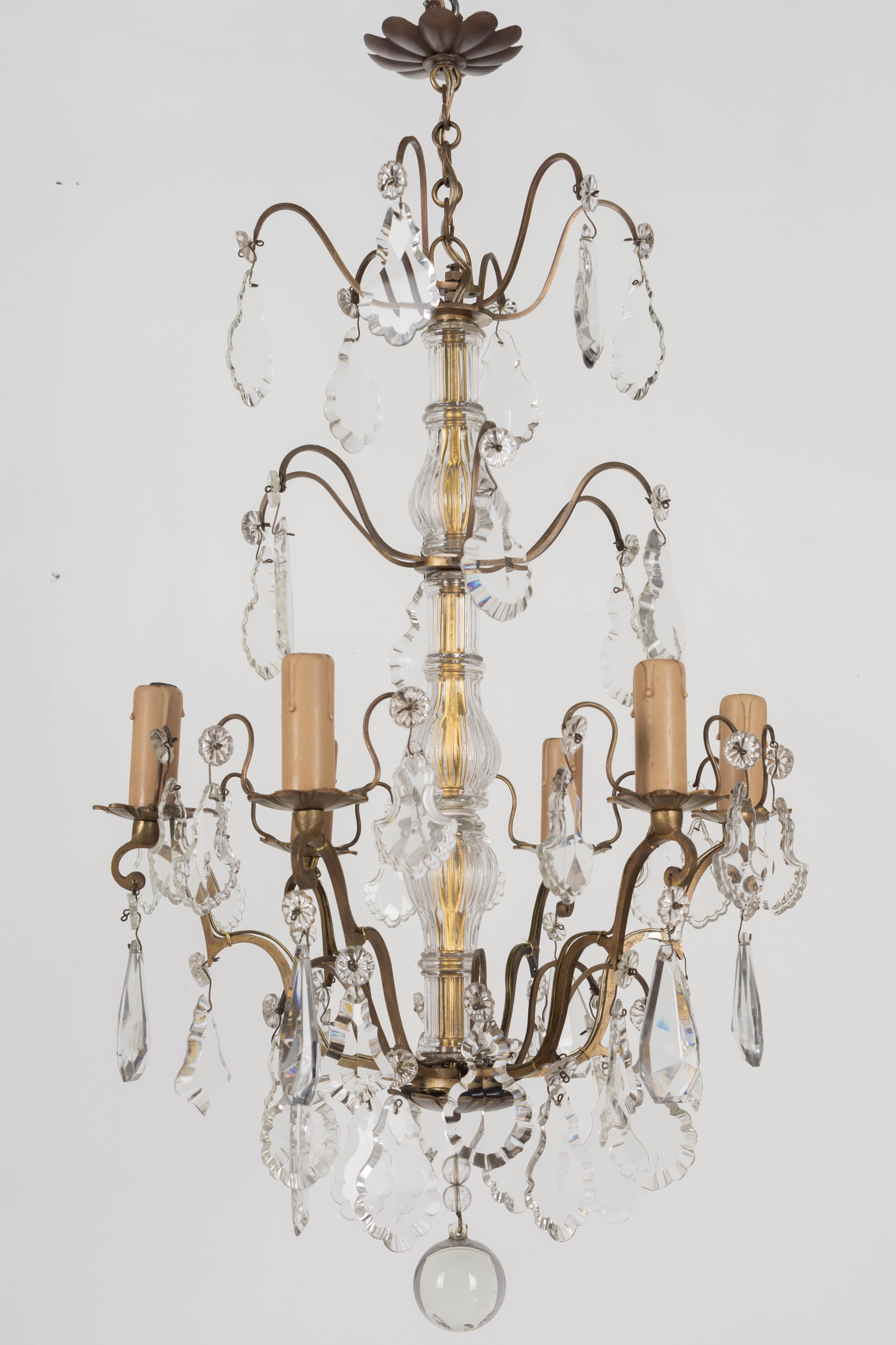 A French Louis XV style six-light chandelier with an assortment of crystal prisms with rosettes, center columns, and large crystal sphere. Brass frame with cast brass bobeches has been cleaned but not polished. Original candle covers. Rewired and in