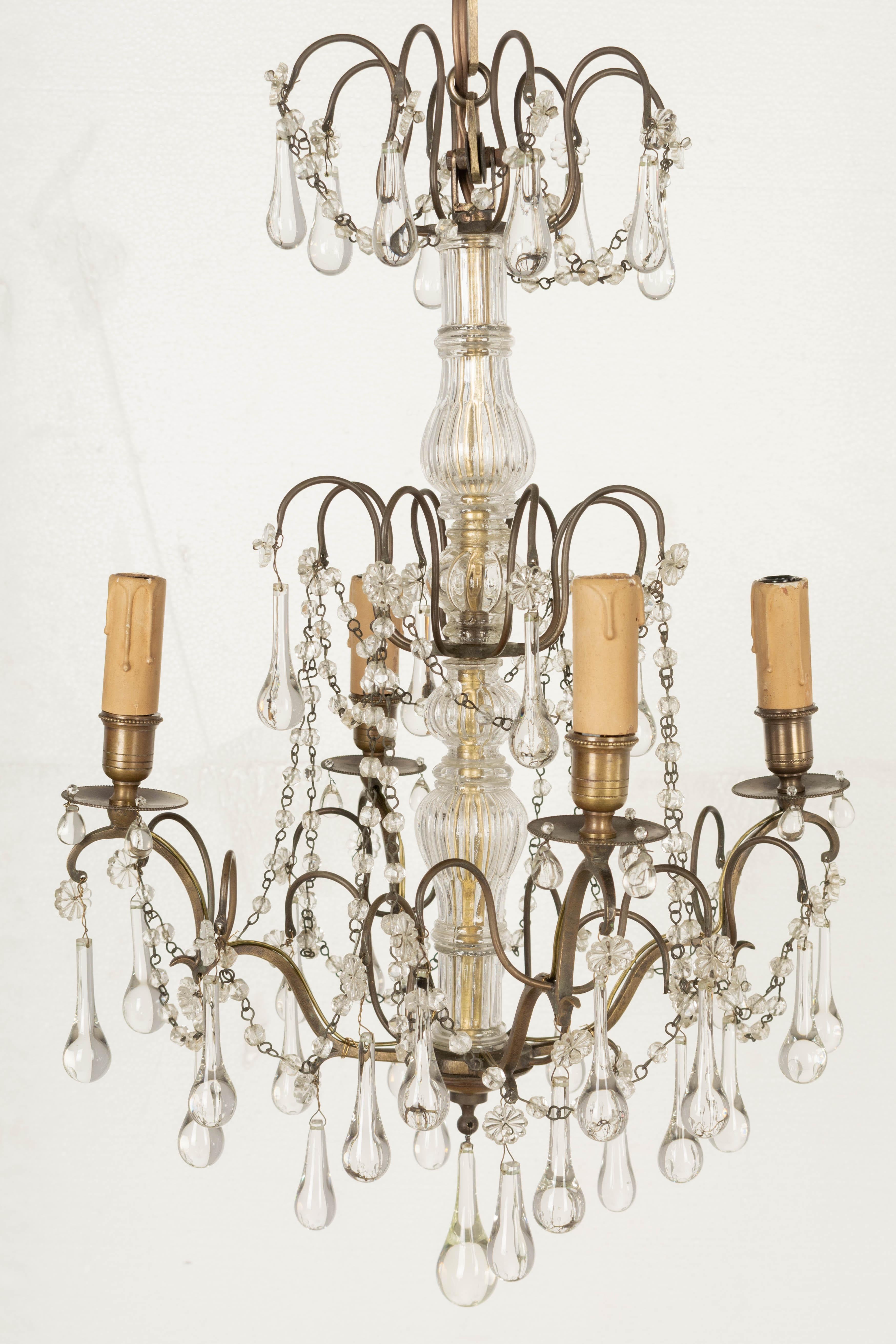 A French Louis XV style four-light brass chandelier with glass center columns and clear crystal teardrops with rosettes. Original candle covers. Rewired with new sockets. Circa 1900-1920.
24