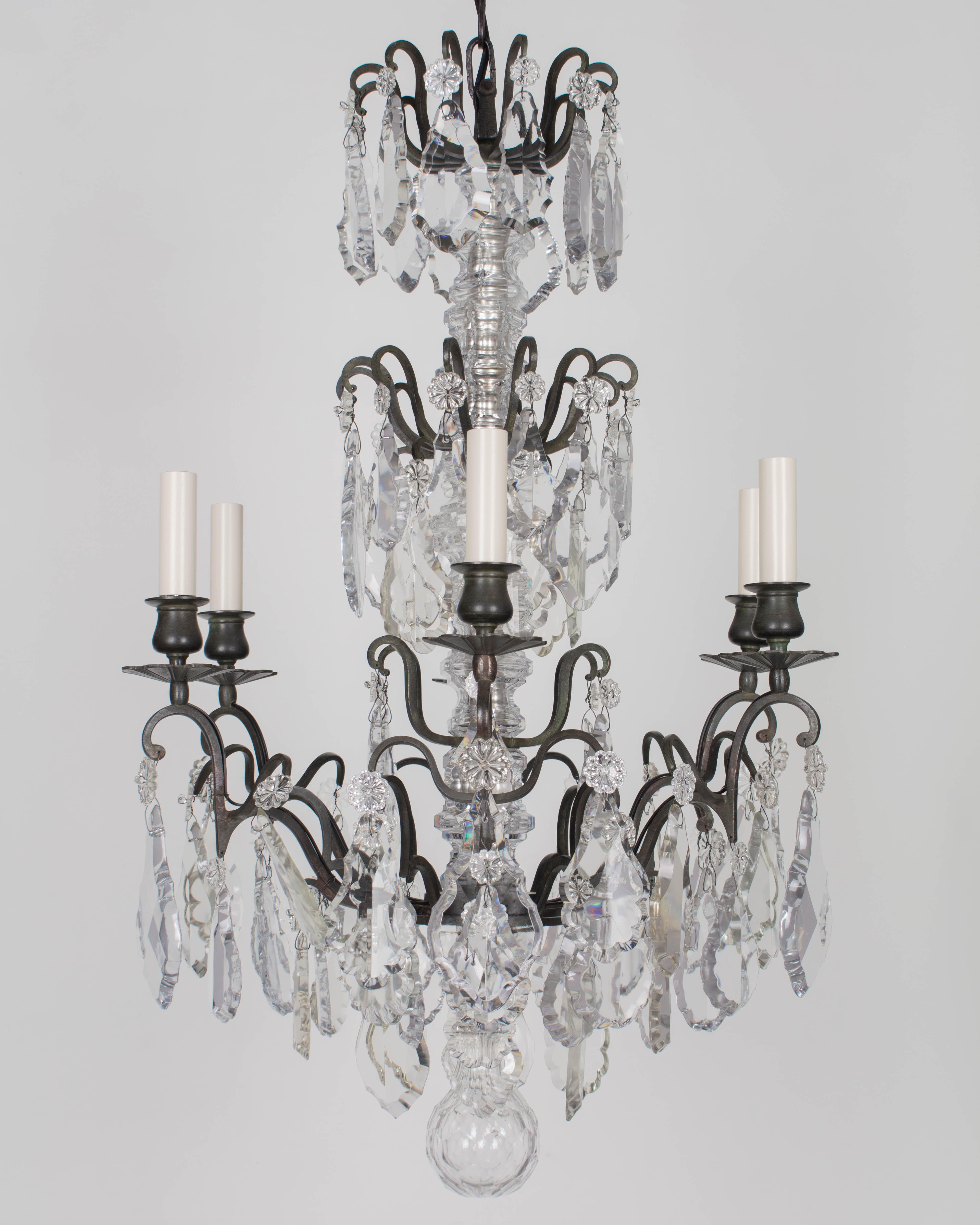 A French Louis XV style six-light chandelier with an assortment of crystal prisms and pendalogues with rosettes, center columns, and large faceted crystal sphere. Heavy solid brass frame with cast brass bobeches. Beautiful dark verdigris patina.