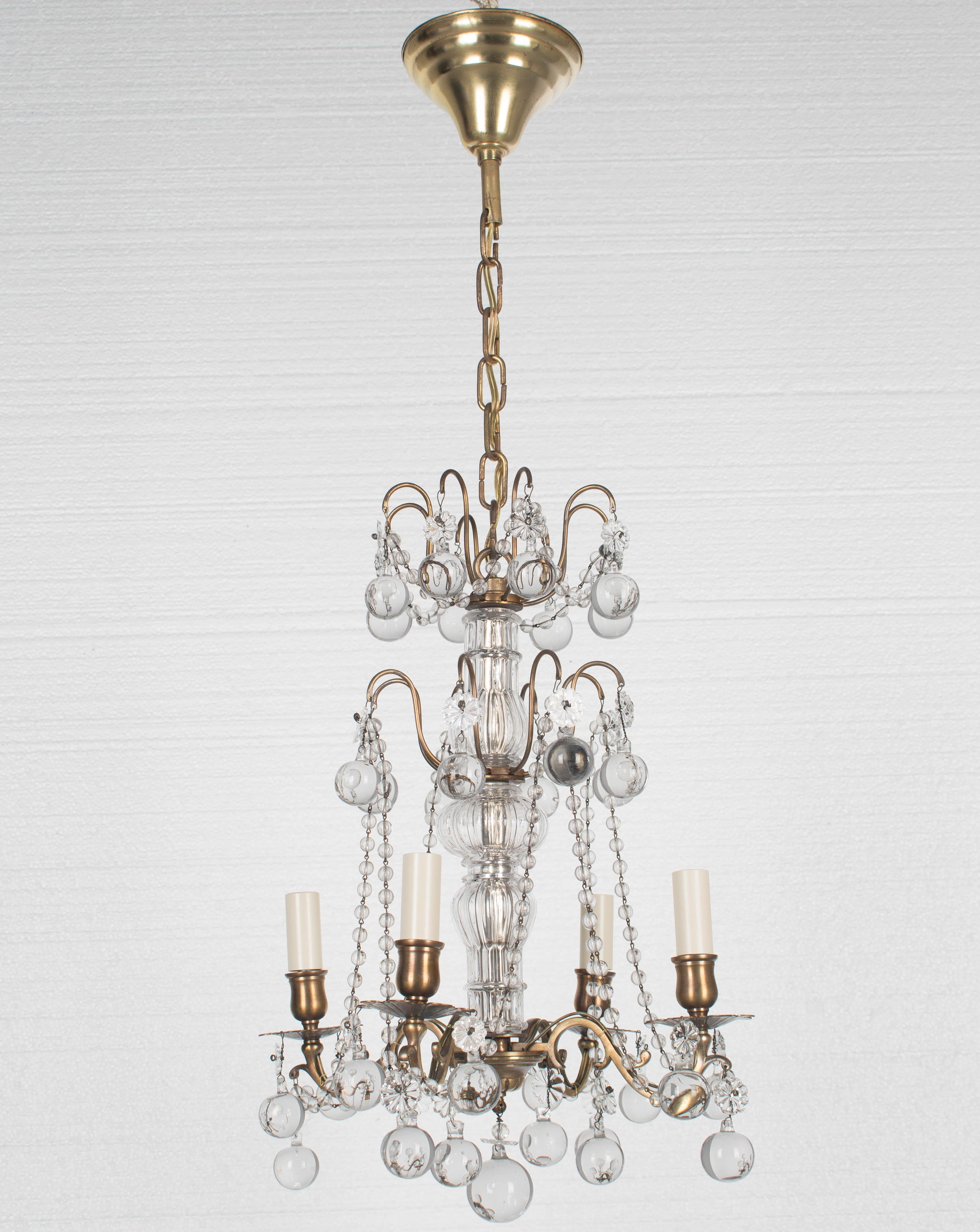 Lampadario a quattro luci in stile Luigi XV francese con struttura in bronzo fuso e colonne in vetro scanalato, sfere di cristallo con rosette e catene di perline. Tettuccio e catena. Tutto originale. Ricablato con nuove prese e copricandela. Per