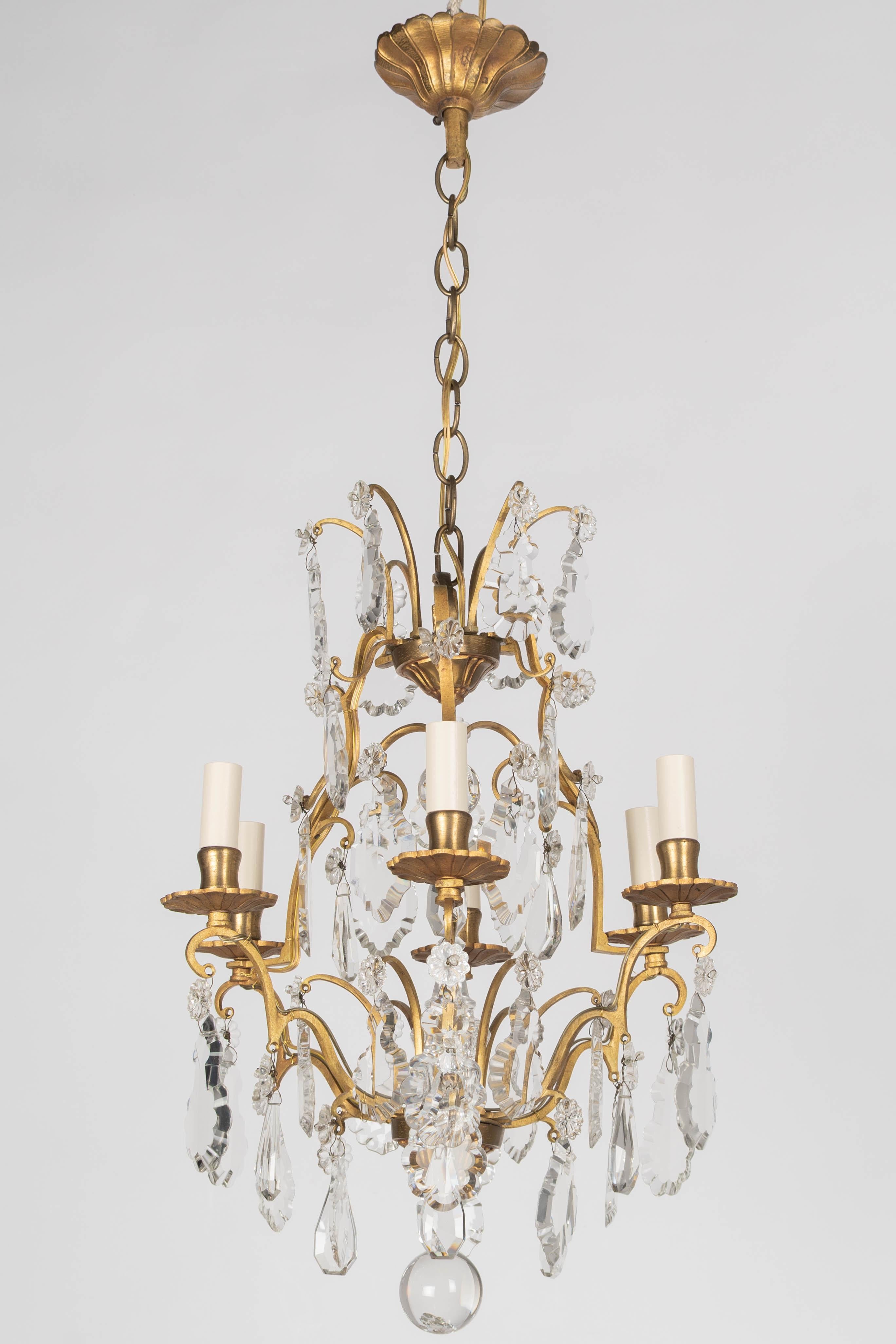 Lampadario a sei luci in stile Luigi XV dell'inizio del XX secolo con un assortimento di prismi e pendoli di cristallo, lancia centrale e sfere di cristallo. Struttura in ottone massiccio con bobeches e coppe per candele in ottone fuso. Colata