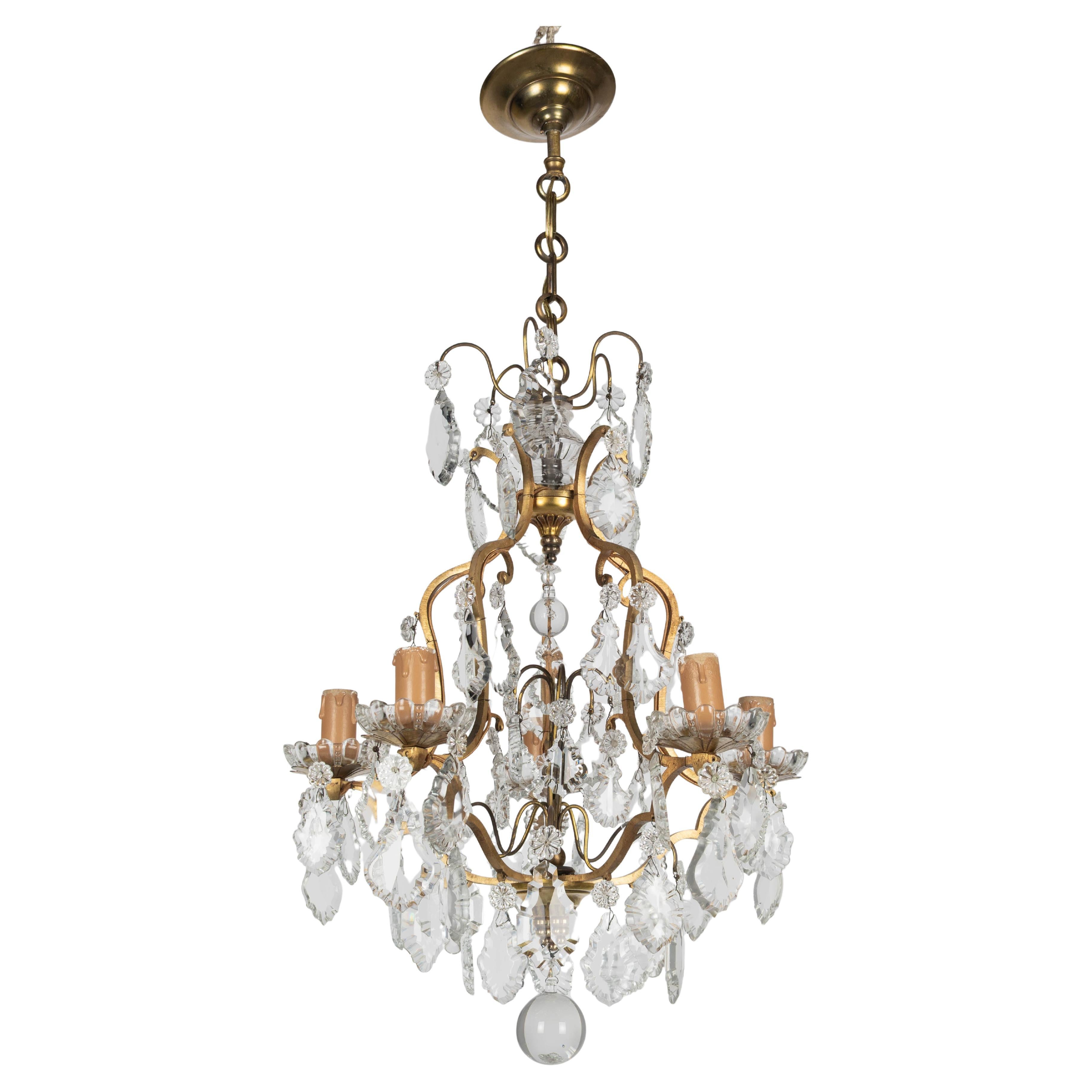 Lustre français à cinq lumières de style Louis XV avec un assortiment de prismes et de pendentifs en cristal avec des rosettes et des sphères en cristal. Cadre en laiton massif avec boules de verre, cristaux d'origine, couvercles de bougies et
