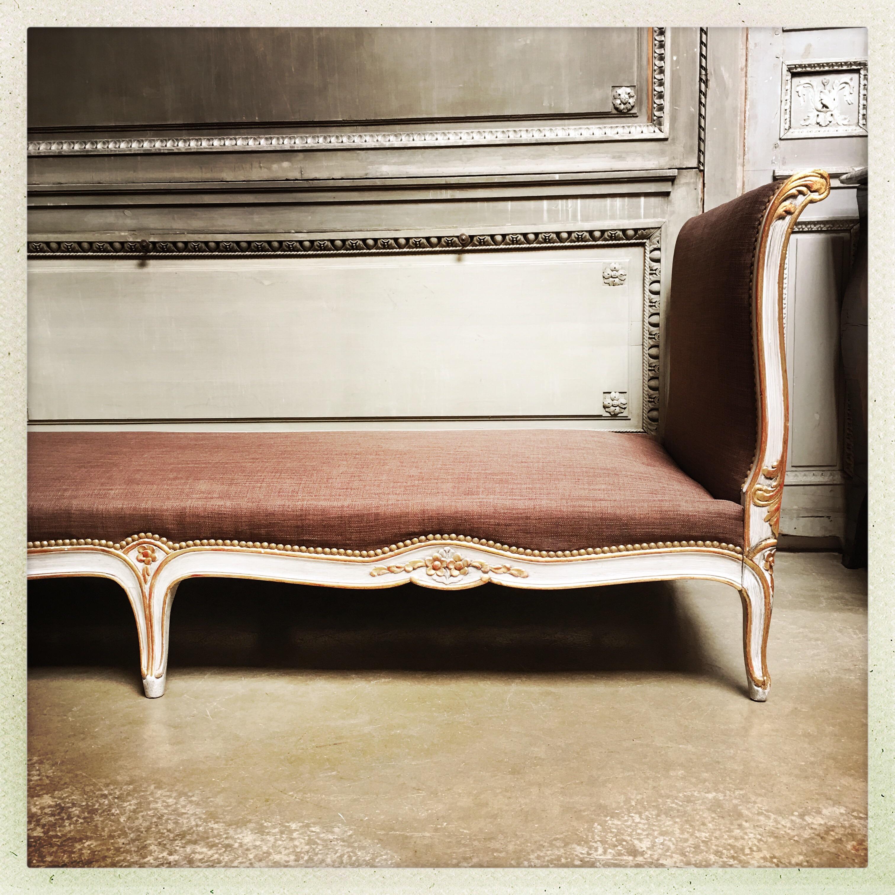 A French Louis XV style daybed with a painted and parcel gilded finish.