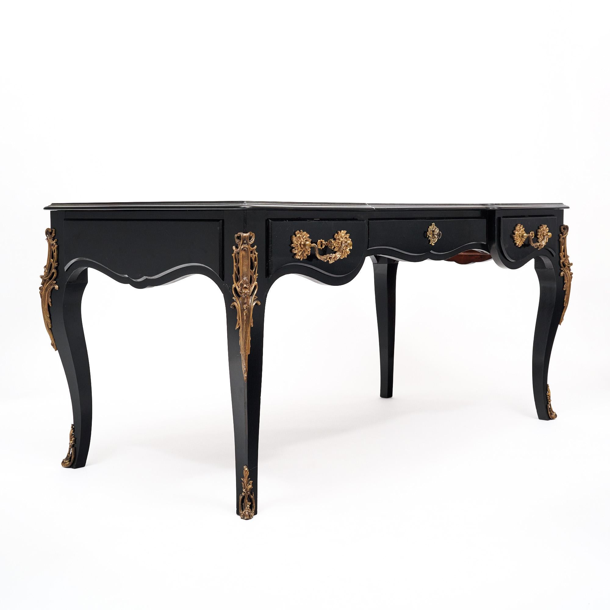 Antico scrittoio francese in stile Luigi XV realizzato in legno massiccio ebanizzato e rifinito con una lucida finitura francese di qualità museale. La scrivania ha il piano originale in pelle nera. Ci sono tre cassetti a coda di rondine, tutti