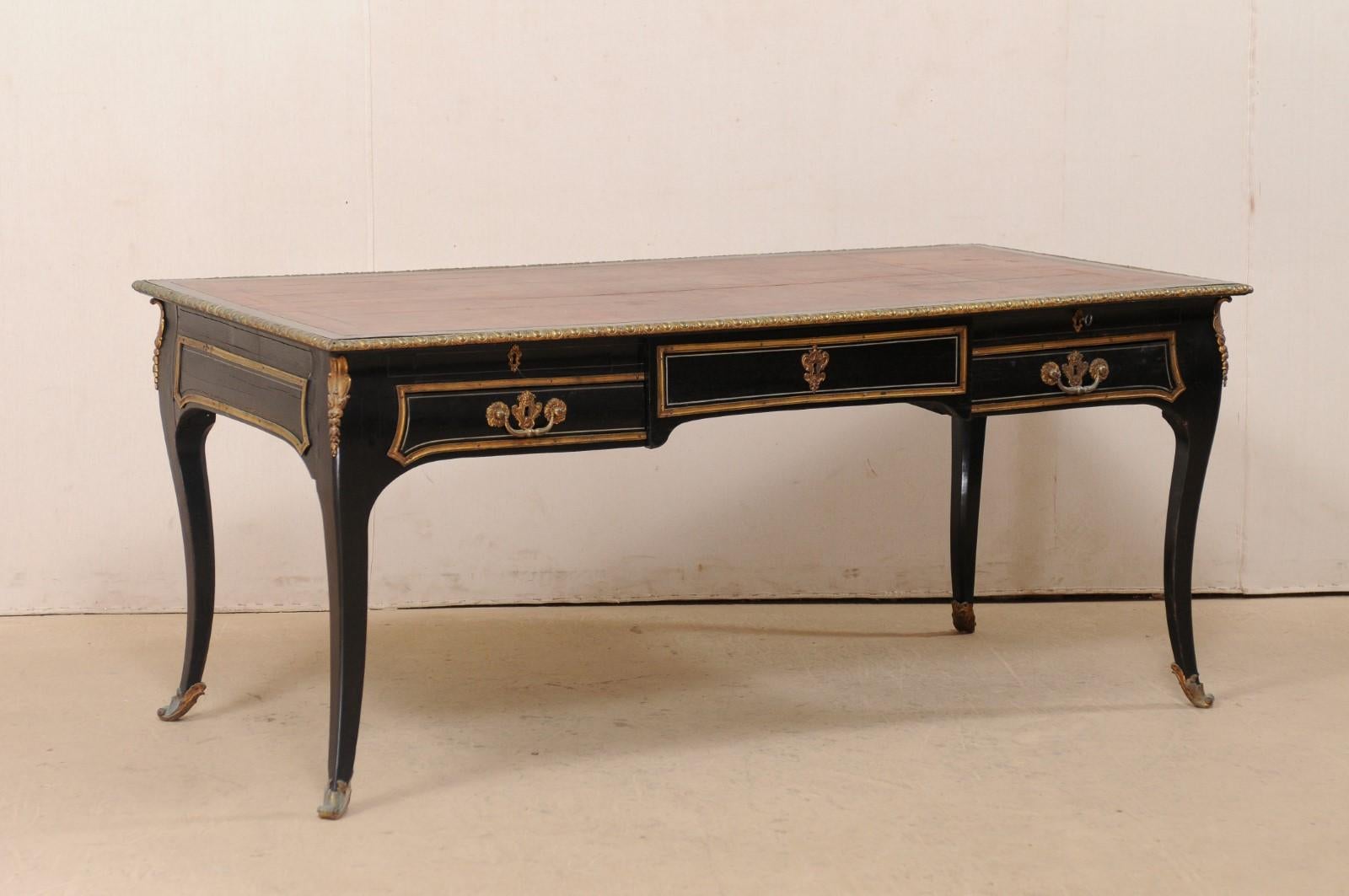 A French Louis XV style desk, with leather writing pad top, from the 19th century. This antique table from France has been designed in the Louis XV style with top fitted with a leather writing pad and top edging adorn in egg-and-dart carved trim.