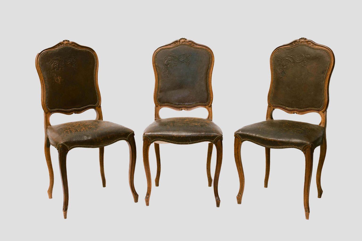 Carved walnut, Louis XV french style, dining chairs with cabriole legs, tacked, embossed leather, and a carved shell crest.