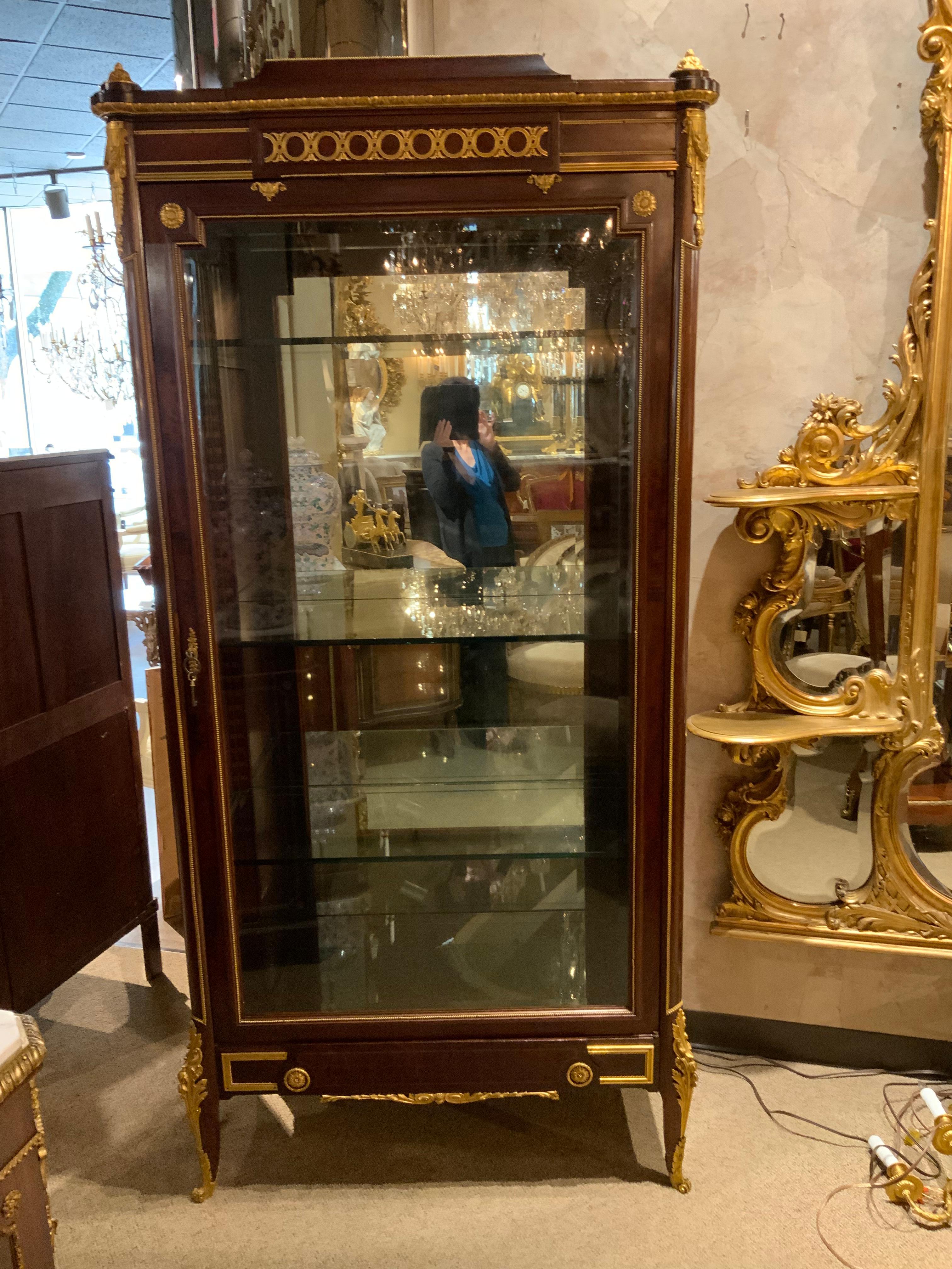 Exceptional quality vitrine with mirrored back having four glass shelves.
Beautifully cast bronze dore mounts decorate this piece. Beveled glass 
Door. Lighted, shelves are movable.