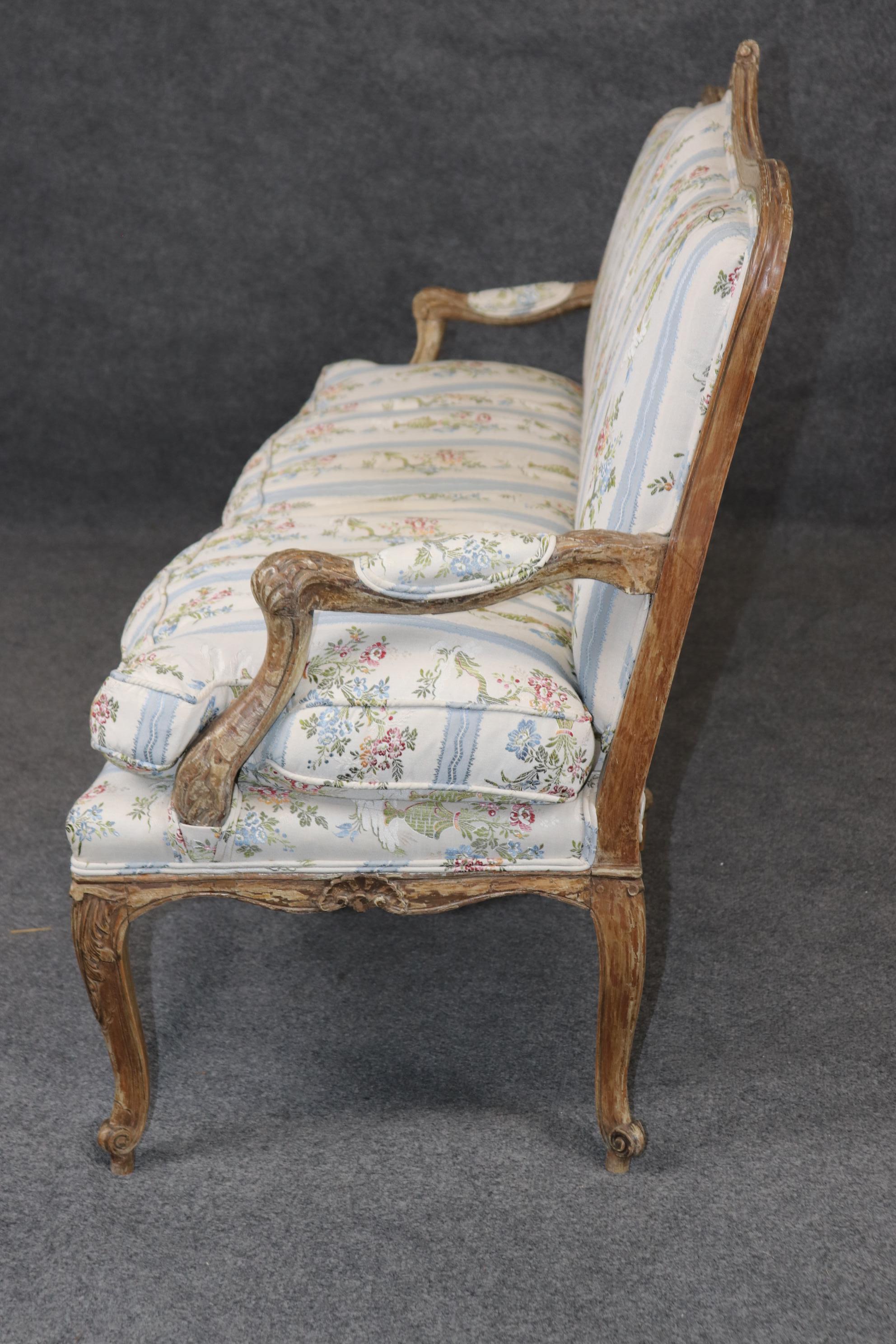 This is a beautiful time-worn distressed painted French L:ouis XV Settee that dates to the 1890-1910s era and is in good original condition. The settee is graceful and sophisticated and beautifully carved. The upholstery is still in useable