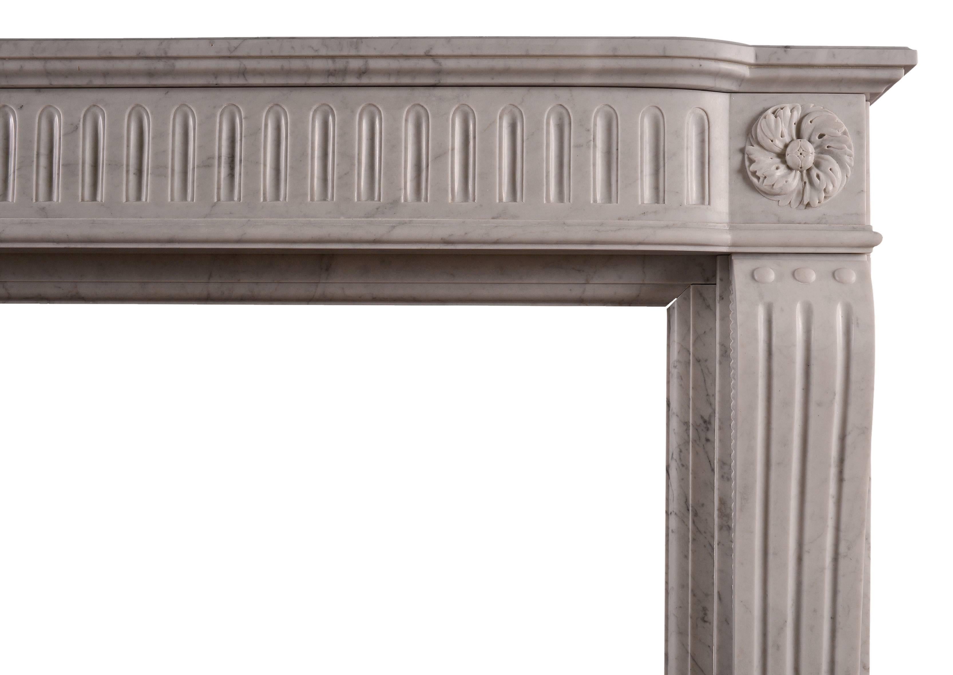 Ein Kamin aus Carrara-Marmor im Stil von Louis XVI. Die geformten, kannelierten Pfosten werden von geschnitzten, wirbelnden Paterae gekrönt. Der gewölbte Fries mit passenden Kanneluren und profilierter Ablagefläche darüber, französisch,