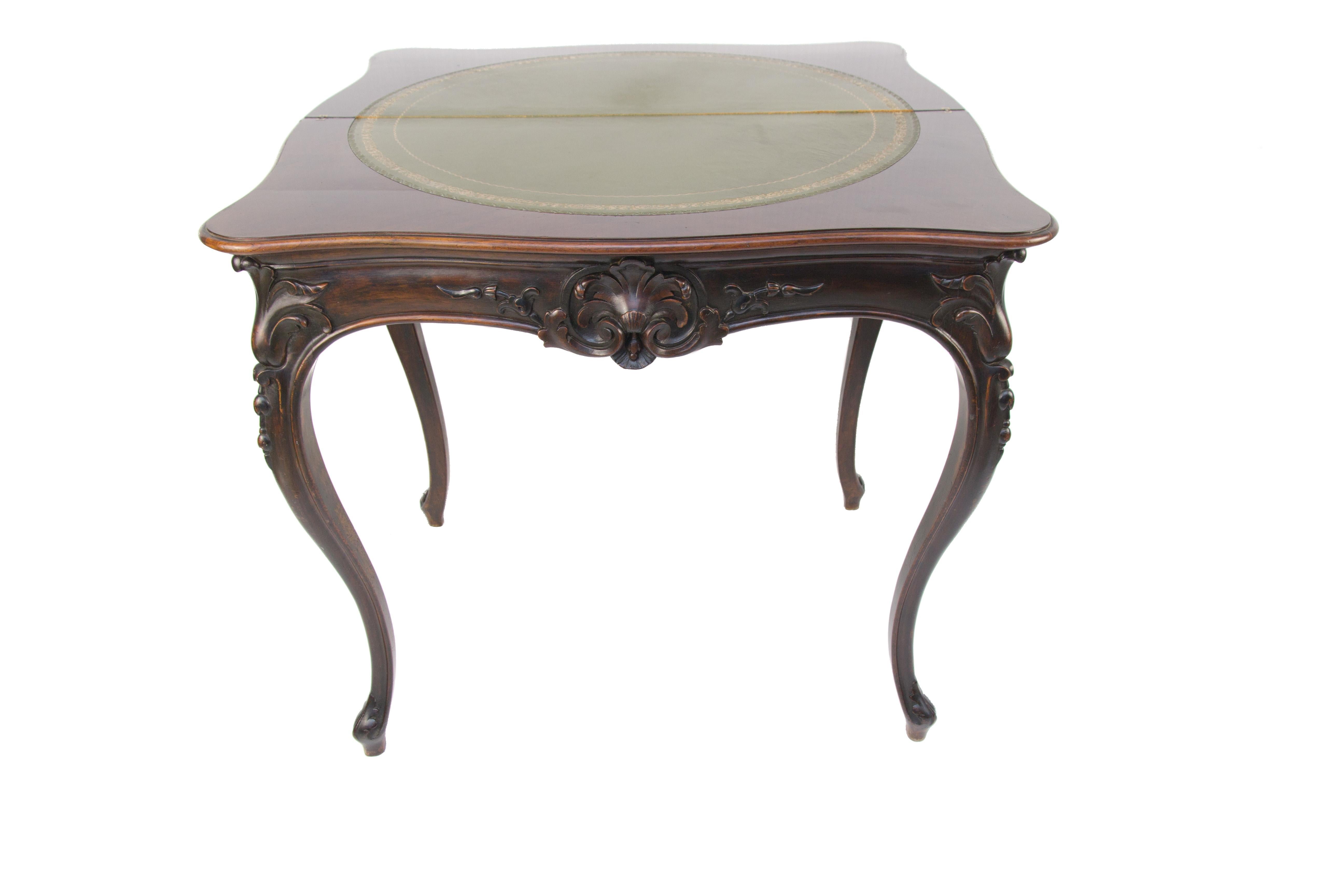 A beautifully carved French Louis XV or Rococo style walnut card table which can either be used as a narrow console table or can open to seat 4 people for games or card play. The top opens to reveal a circular green leather area. The table is raised