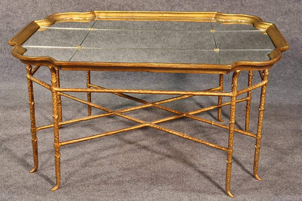 This beautiful table is done in faceted mirror with an entirely gilded gold leaf frame of metal. The hand-wrought iron base evokes the Hollywood Regency era so beautifully.
