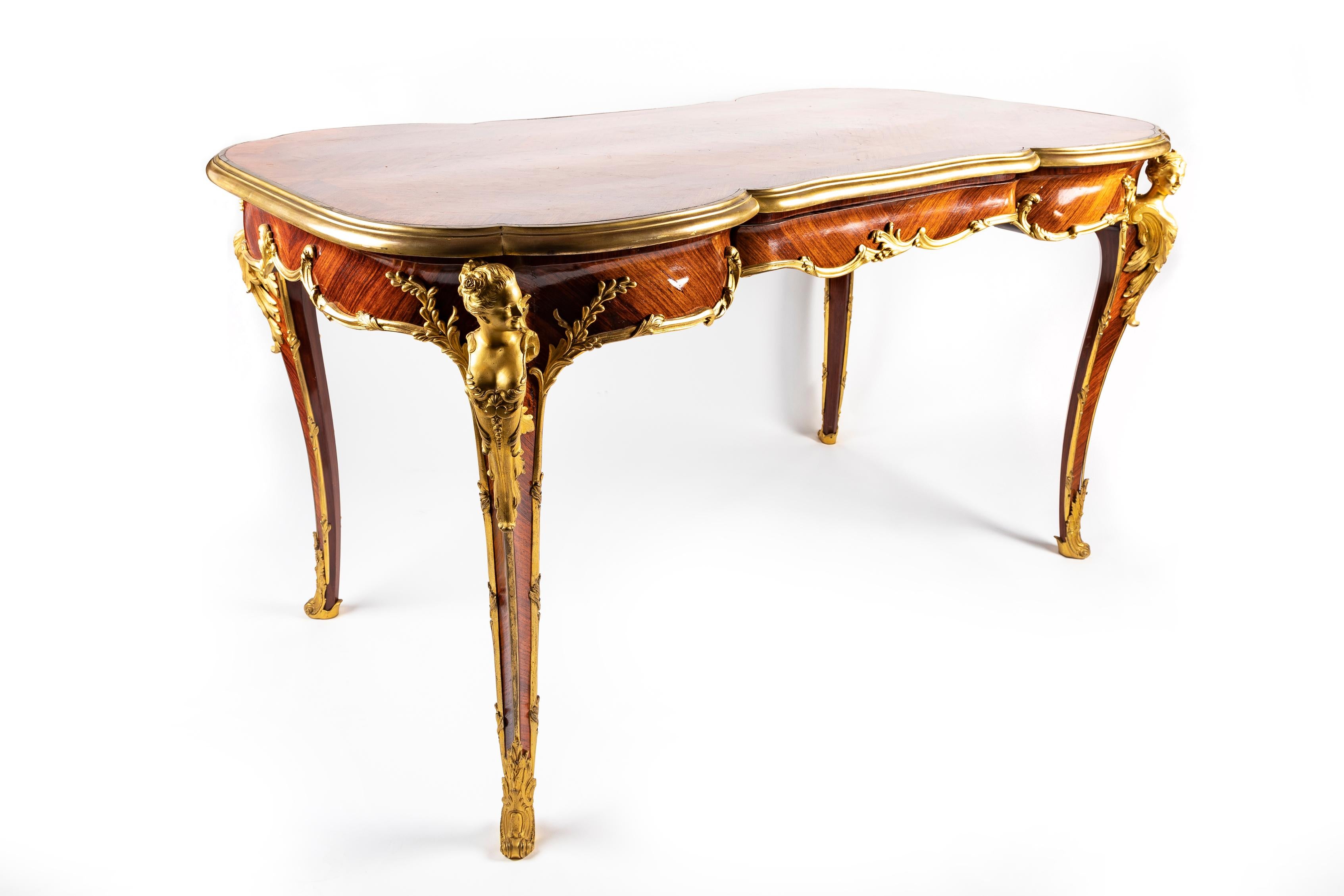 Magnífico buró/escritorio de doble cara del siglo XIX, de estilo Luis XV francés antiguo, con figuras de bronce dorado montadas en madera de rey y marquetería, de forma única. Este espectacular escritorio francés tiene una forma grácil y simétrica