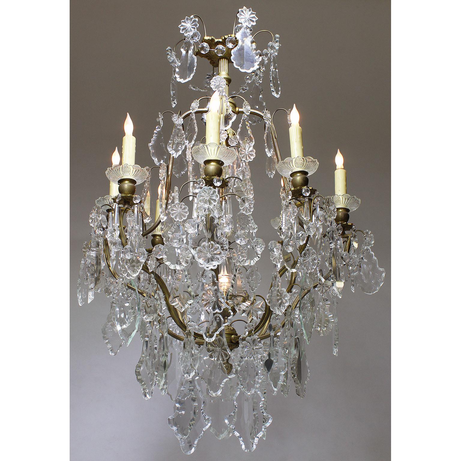 A French Louis XV style gilt-metal and cut-glass ten-light chandelier. The caged body surmounted with ten scrolled candle-arms, each fitted with molded glass wax-holders, with two interior lights, the bottom light inside a glass obelisk, all
