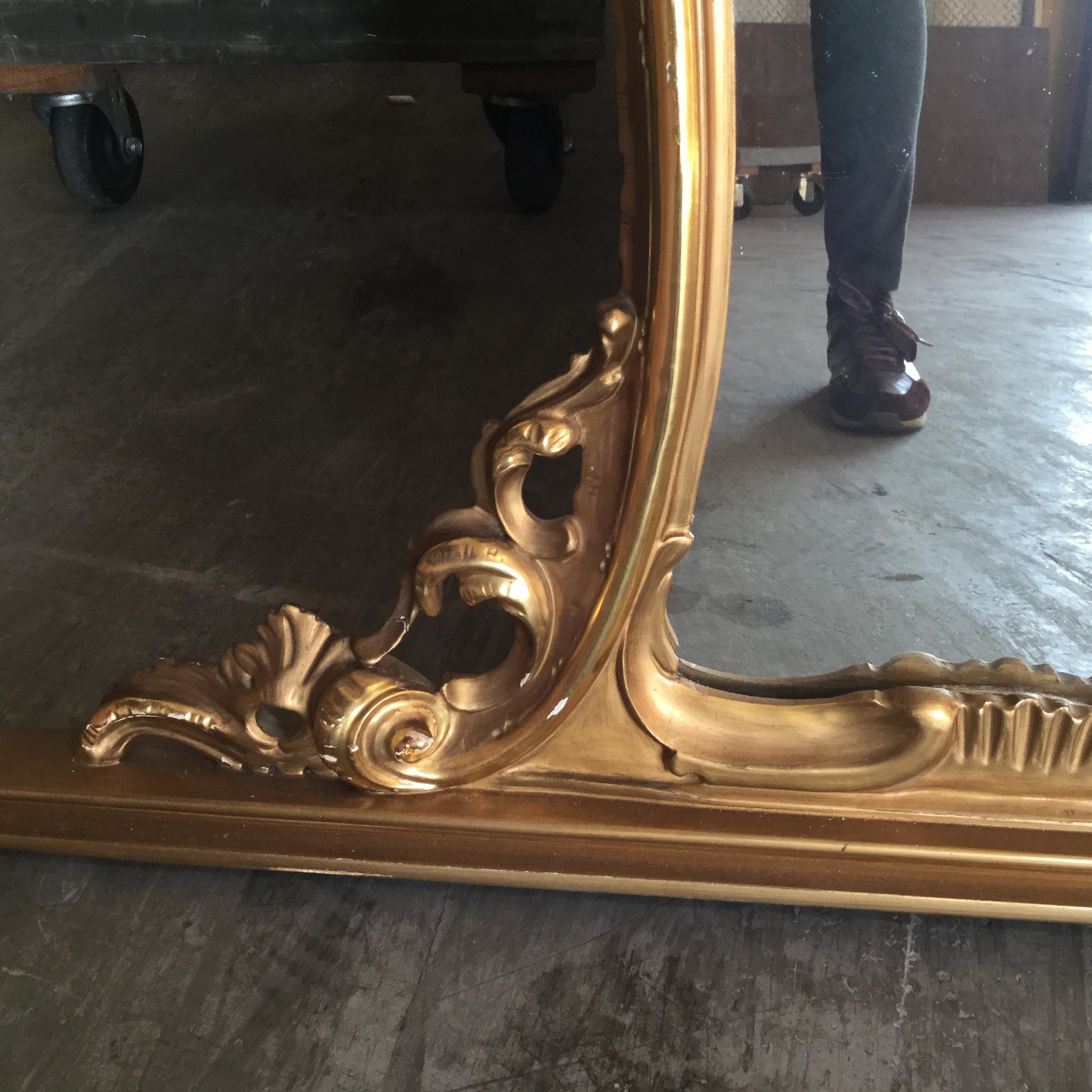 This large French mirror features a real gilt carved frame with beautiful carvings. In the Louis XV style, this mirror is perfect over a buffet, dresser, or any long piece of furniture. The top and sides are scalloped, while the base is straight. An