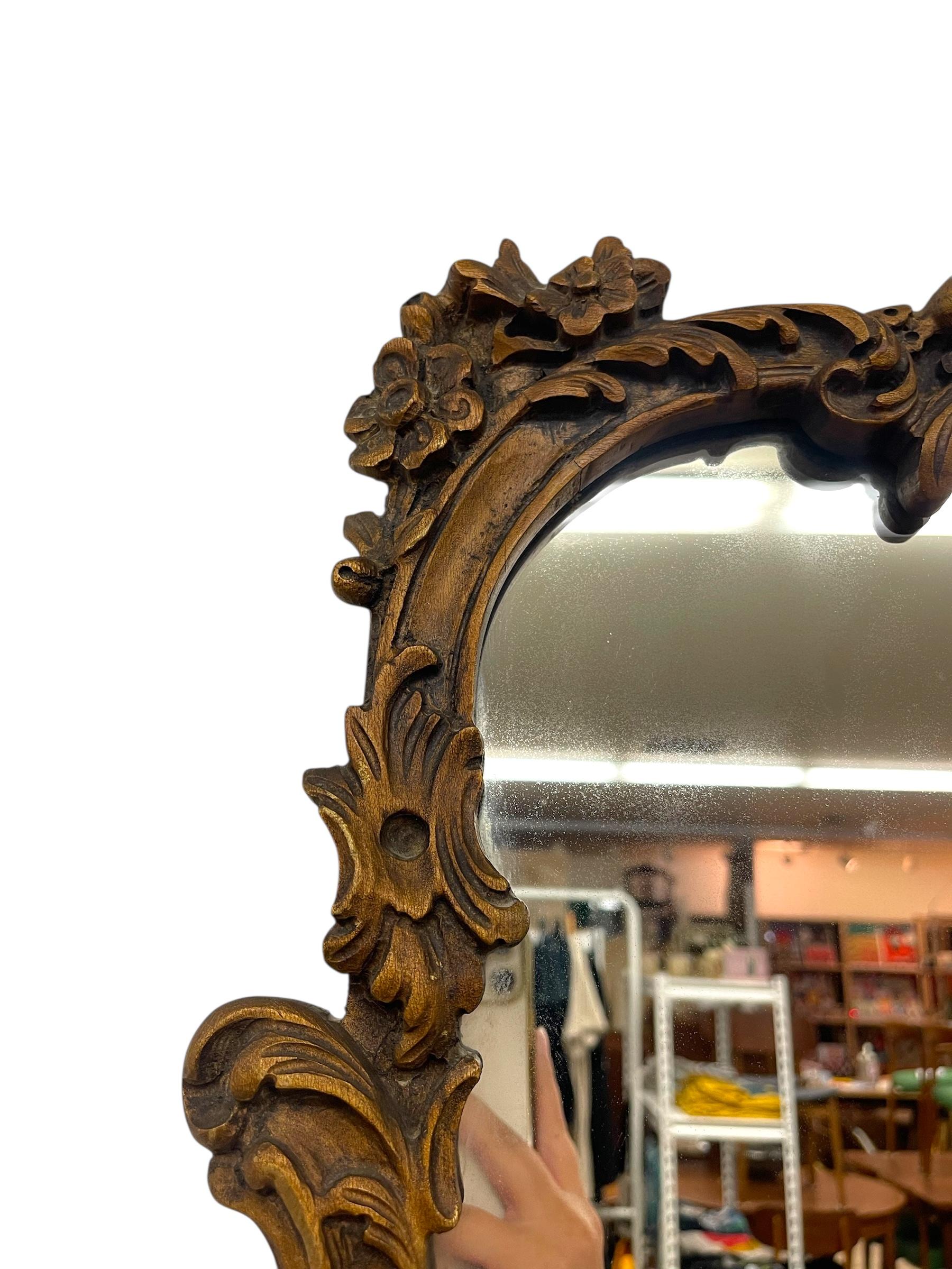 Bois doré Miroir mural en bois doré de style Louis XV avec écusson en coquillage et détails floraux. en vente