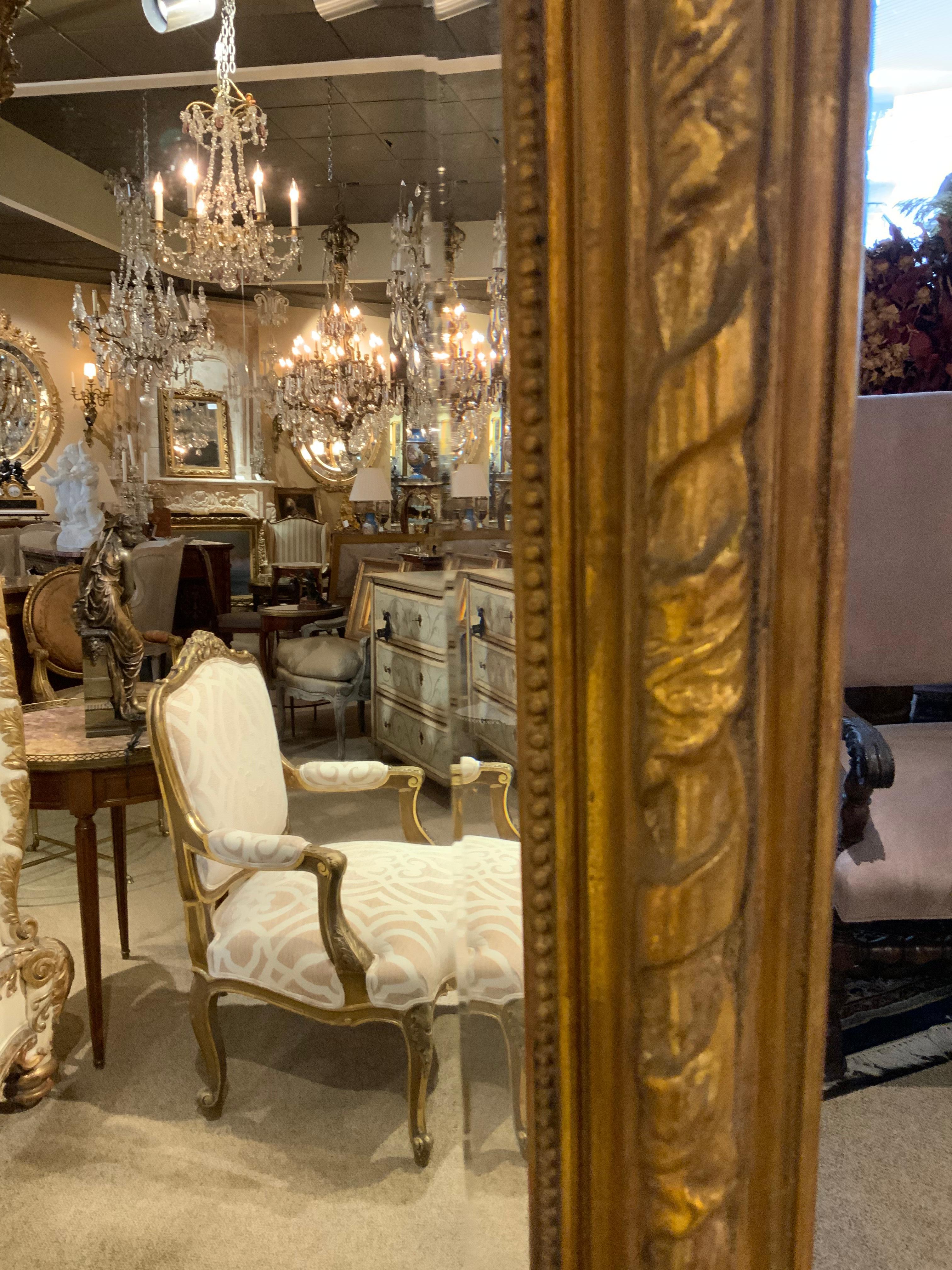 Tall and elegant mirror set in a giltwood frame with a flourishing 
Cartouche centered at the top. It has a large bevel which further
Enhances the desirability of this exceptional mirror. A floral and foliate 
Design is woven into the scrolled