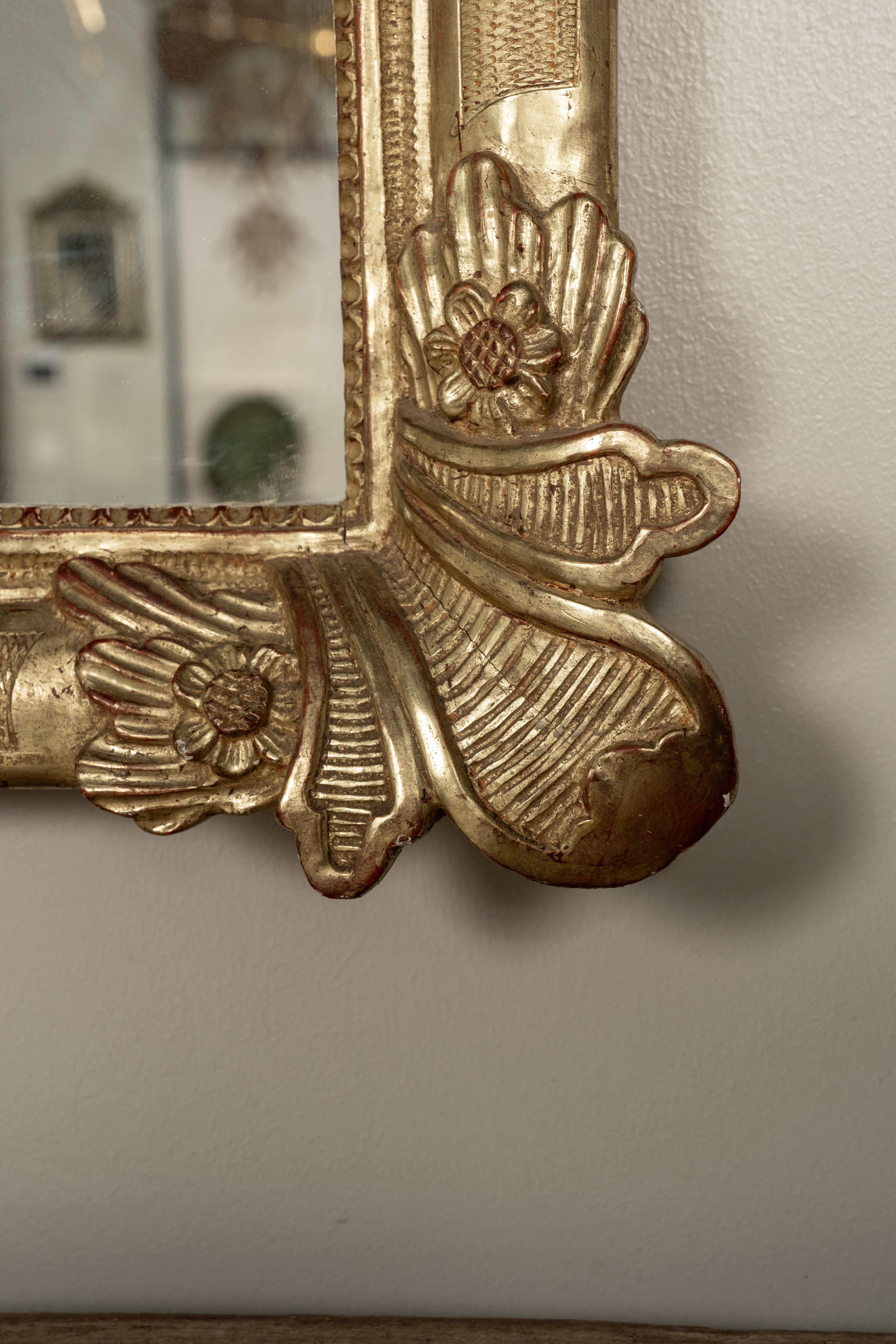 Miroir en bois doré de style Louis XV avec cartouche.
Ce miroir en bois doré de style Louis XV, datant de la fin du XIXe siècle, présente un magnifique motif de feuilles sculptées à chaque coin, ainsi qu'un superbe cartouche central au