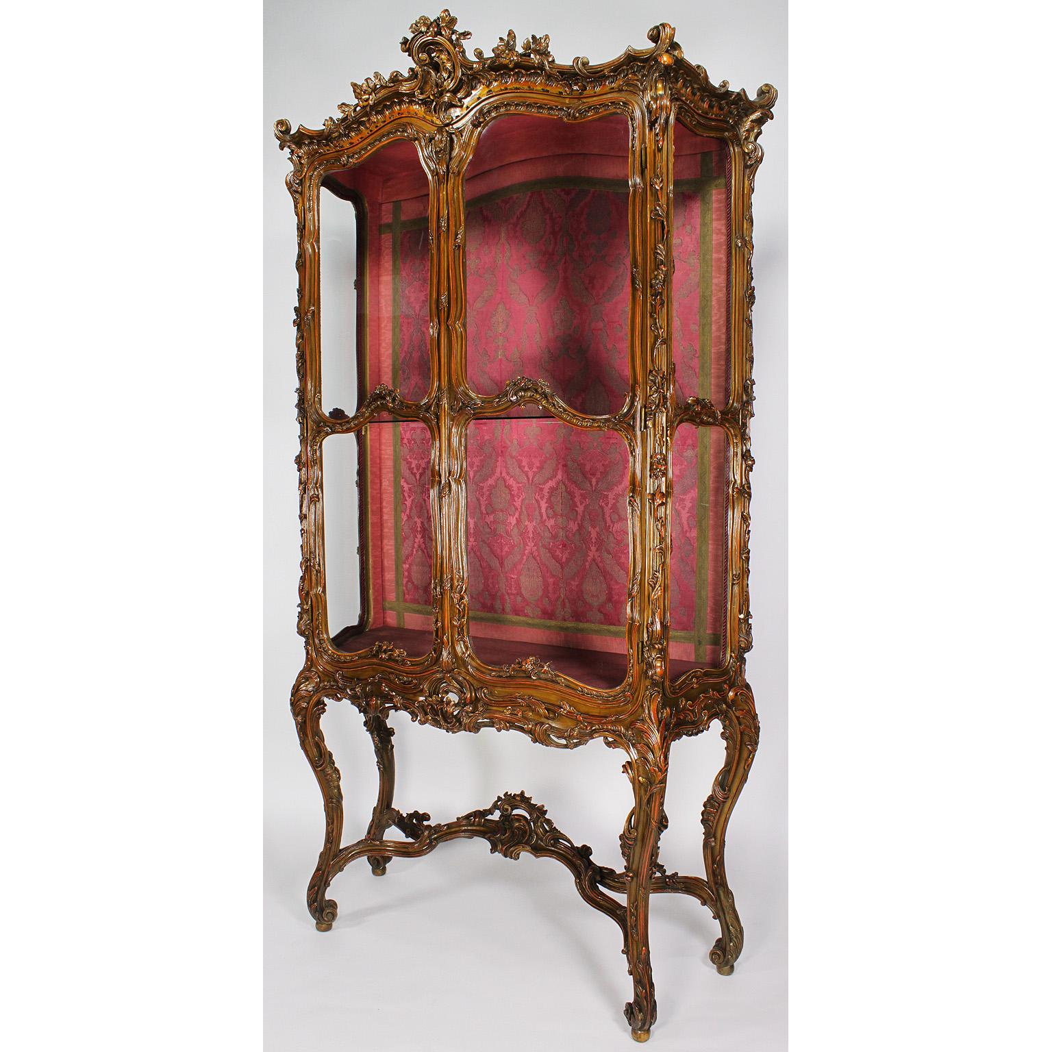 A very fine and palatial French 19th century Louis XV style giltwood ornately carved two-door vitrine display cabinet of serpentine form with foliate and shell carvings, surrounding two glazed bombé front doors, circa: Paris, 1870-1880.

Measures: