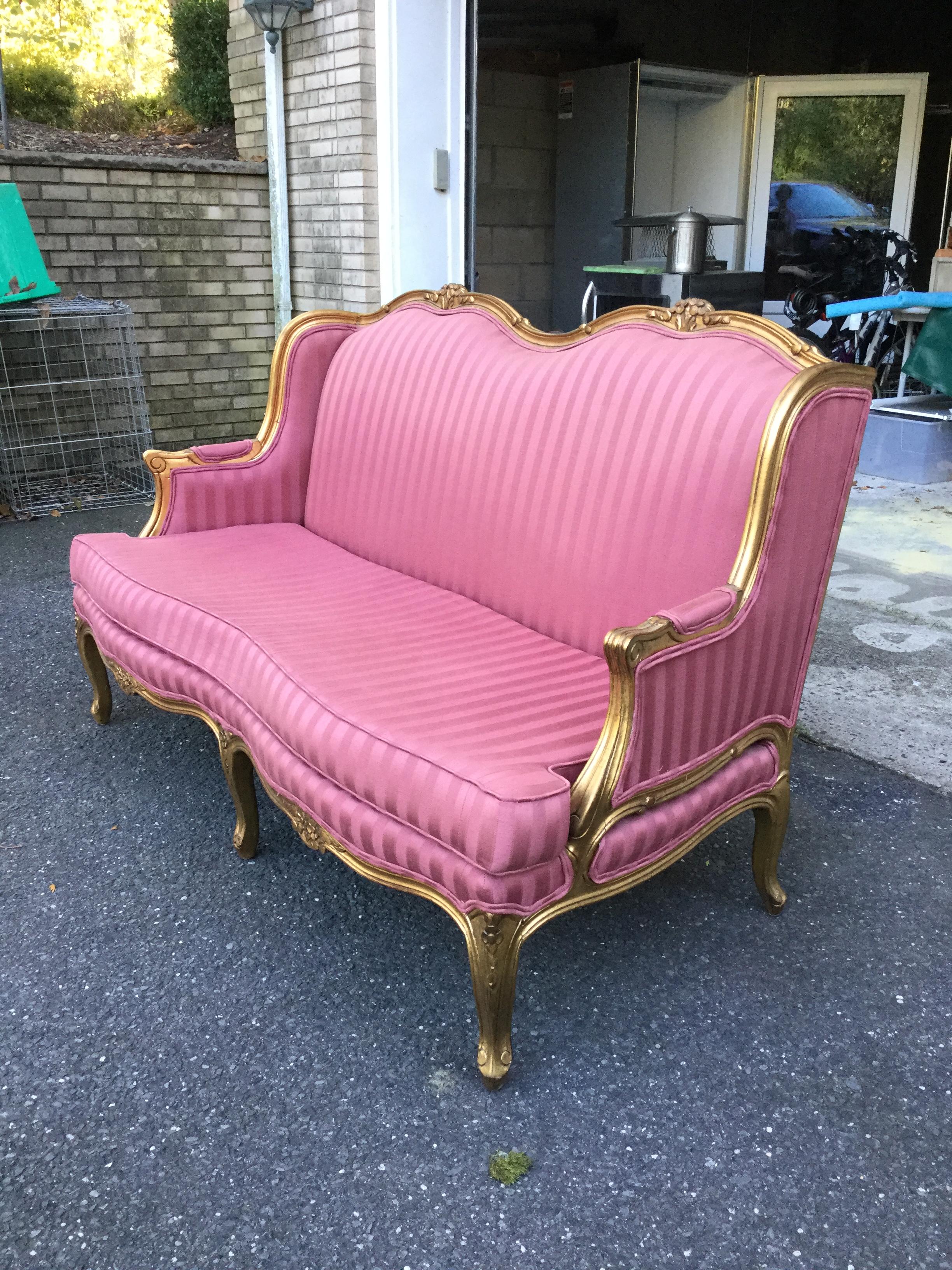 Beautiful and elegant, this vintage Louis-XV style settee features a gold, carved frame and a pink-stripe upholstery fabric. The fabric is original, however it is in mint condition without any stains or tears. The gold, carved frame is enhanced with