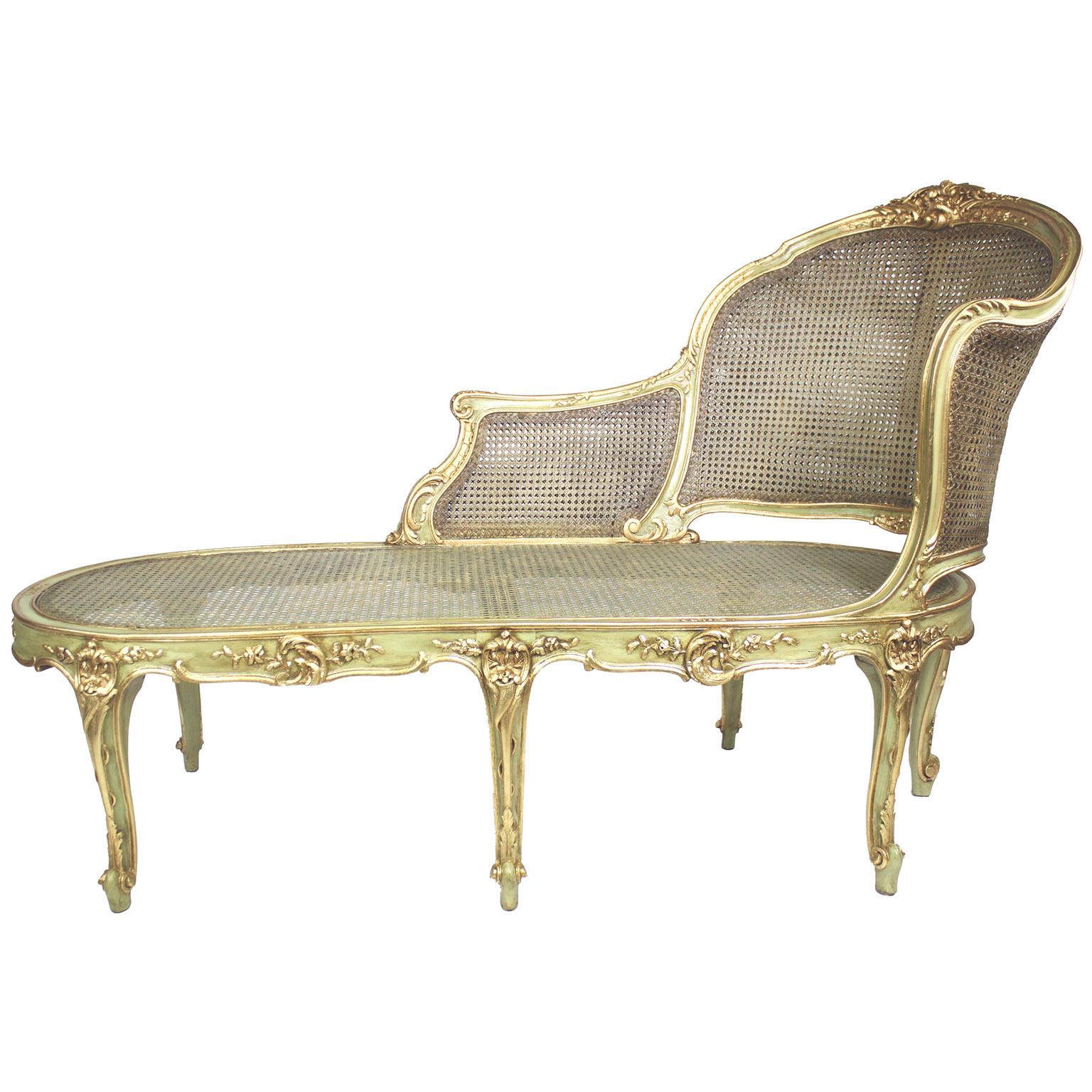 A French Louis XV Style Green-Lacquered and Parcel Giltwood Carved Chaise Lounge Armchair. The rounded backrest carved and caned frame in the shape of an extended armchair, with an extended armrest, parcel-gilt carving details and raised on six