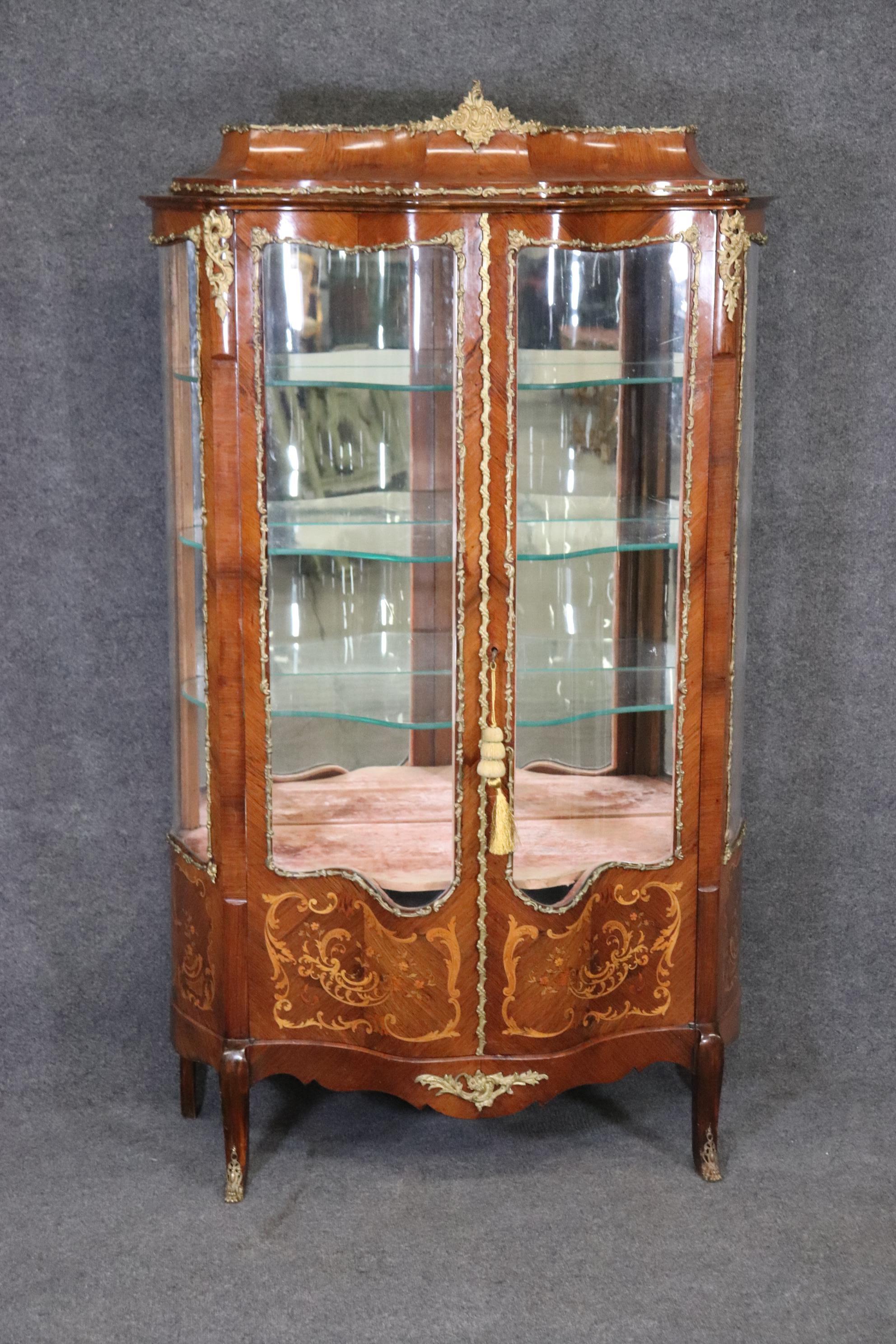 This is a beautiful example of Louis XV style furniture. This curio cabinet is made exceptionally well! From the rich mahogany and brass accents/hardware and then accompanied by the inlaid marquetry work at the bottom front of the piece makes this