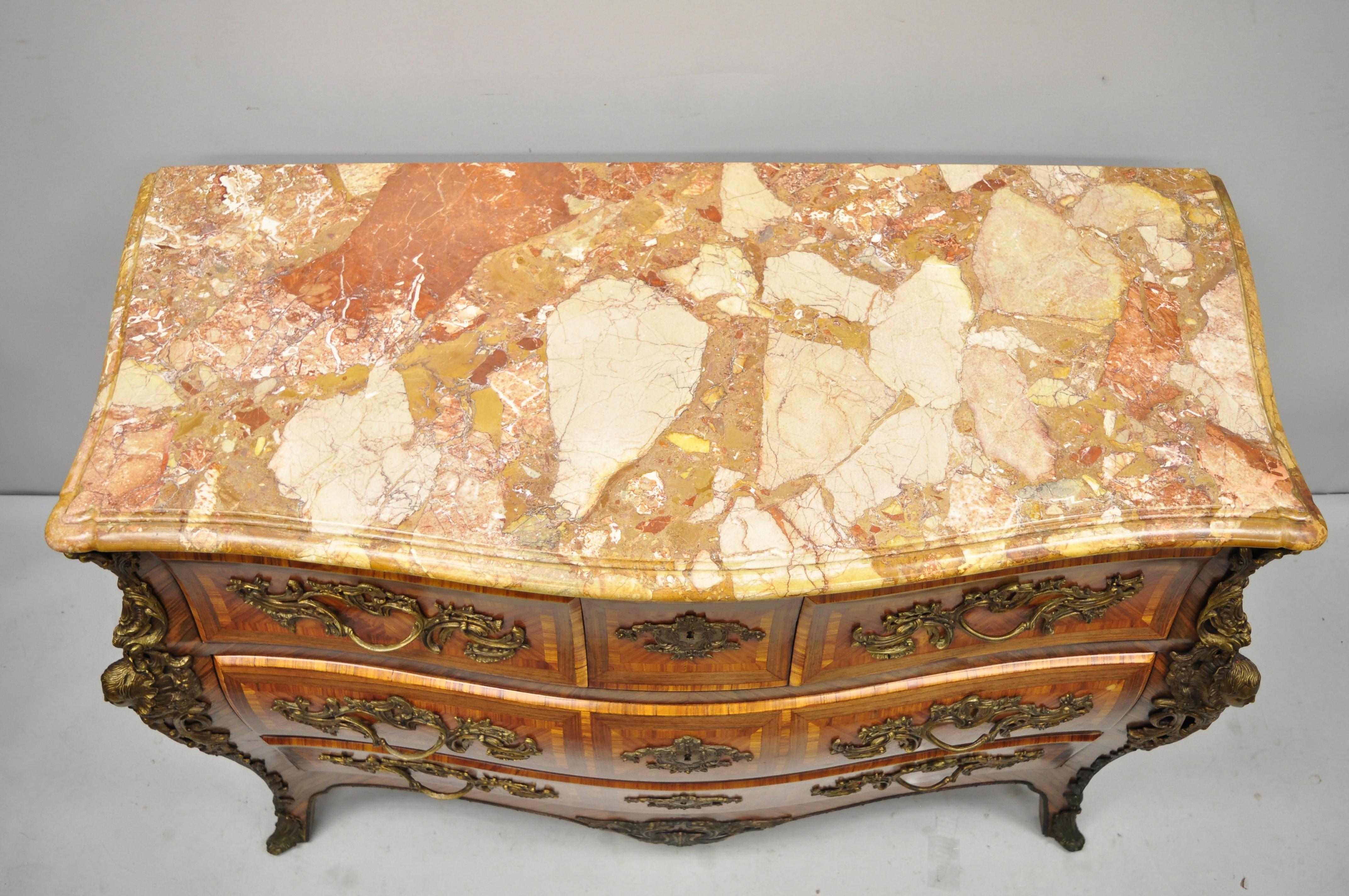 French Louis XV style inlaid marble-top bombe commode chest with bronze figures. Item features stunning marquetry inlay throughout, bronze hardware, bronze male and female faces, shaped rogue marble top with beveled edges, working lock and key, 5