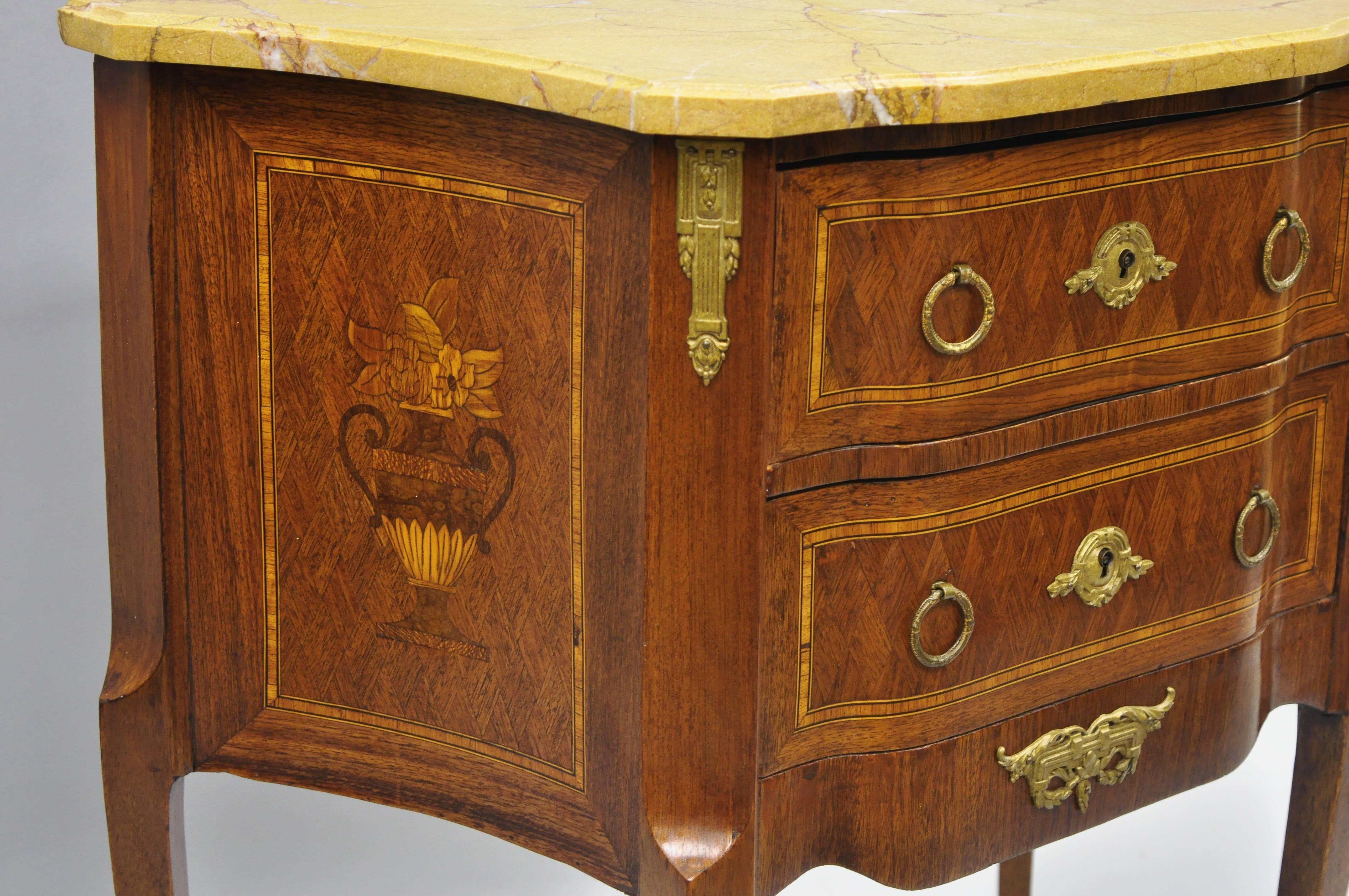 French Louis XV style marble-top bombe commode nightstand. Item features bronze ormolu, satinwood floral inlay, bombe form, shaped marble top, two dovetailed drawers. Early to mid-20th century. Measurements: 30