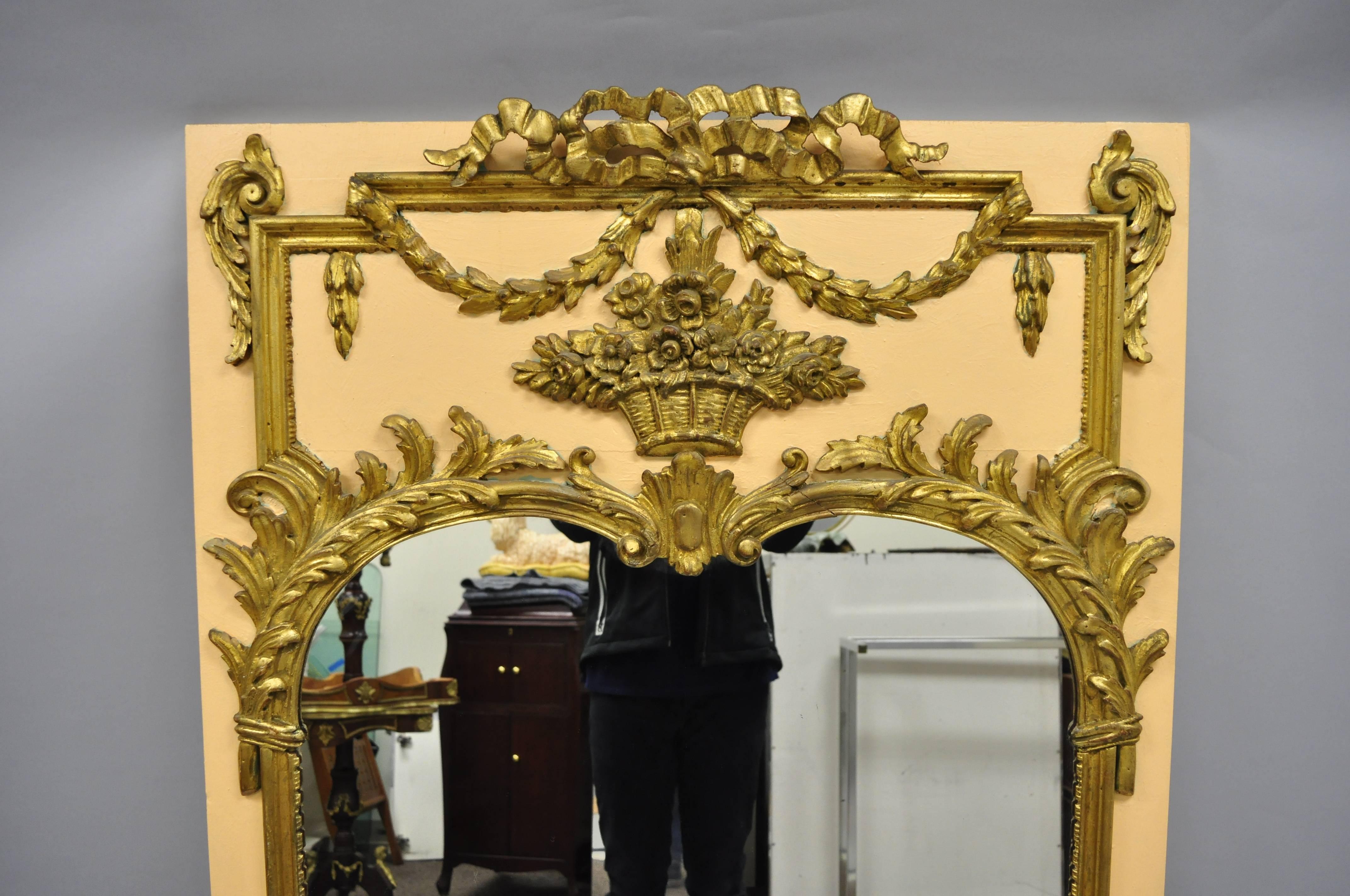 Miroir mural trumeau en bois doré de style Louis XV en pêche et or. L'article présente une finition pêche et or, un bouquet en bois sculpté, un drapé et des volutes de feuilles d'acanthe, un cadre en bois massif, des détails joliment sculptés, un