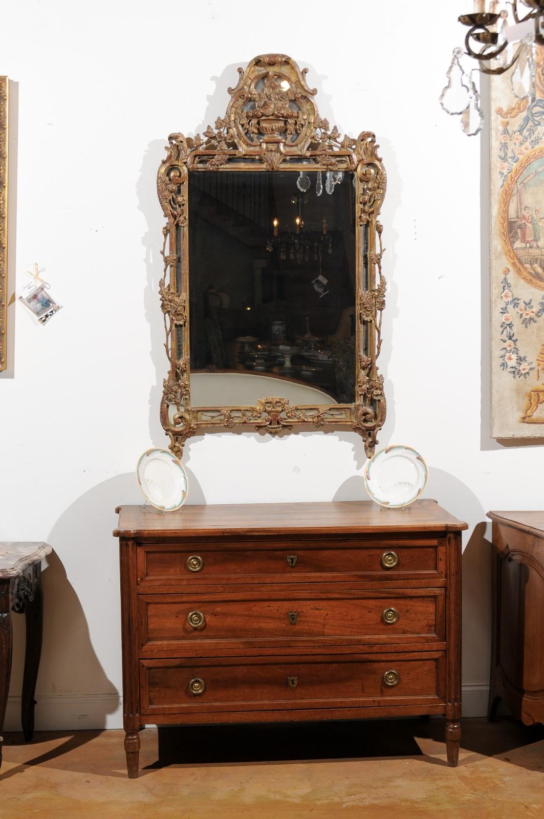 A French Louis XV style carved giltwood mirror from the late 18th-early 19th century, with floral motifs. Born in France after the death of King Louis XVI, this exquisite mirror presents the stylistic characteristics of the Louis XV era. Our eye is