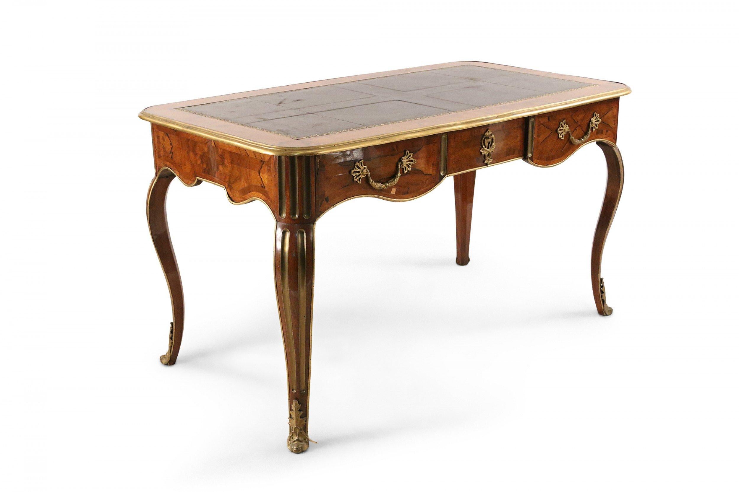 French Louis XV style 19th century kingwood inlaid veneer desk with inset brown leather top with gilt embossed edge design with a brass top border and brass fluted trim legs and feet.