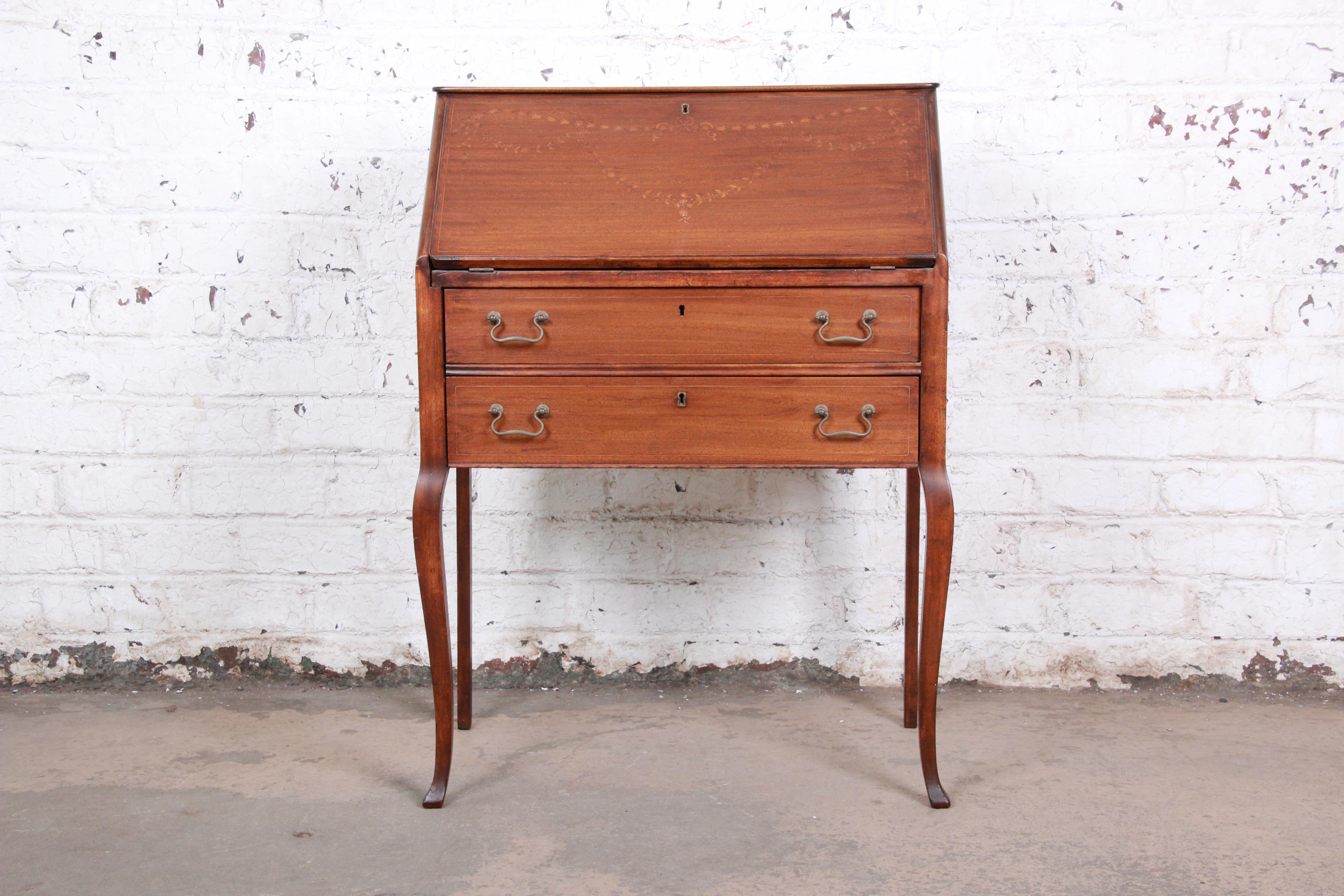 A gorgeous Louis XV style drop-front secretary desk. The desk features beautiful mahogany wood grain, with floral marquetry and mother of pearl inlays. It offers good storage, with six cubbies and a single drawer behind the drop-front and two