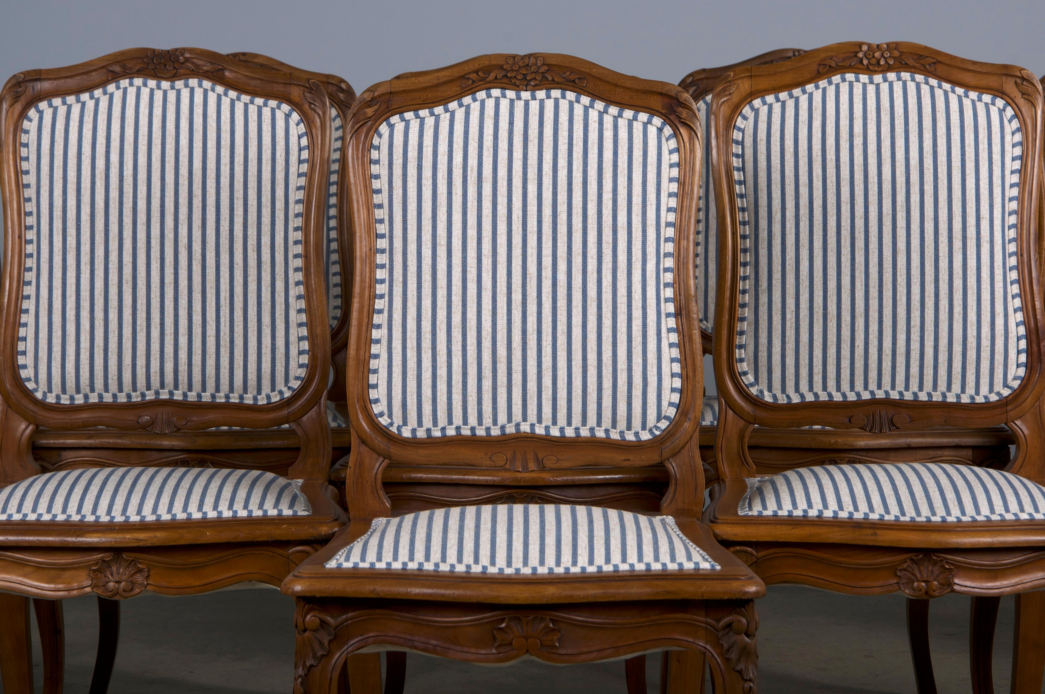 A stunning set of ten early 20th-century French dining chairs in the Louis XV style, sourced from Provence, France. Expertly hand-crafted from solid maple, these chairs feature exquisite hand-carved floral motifs and a naturally aged patina with