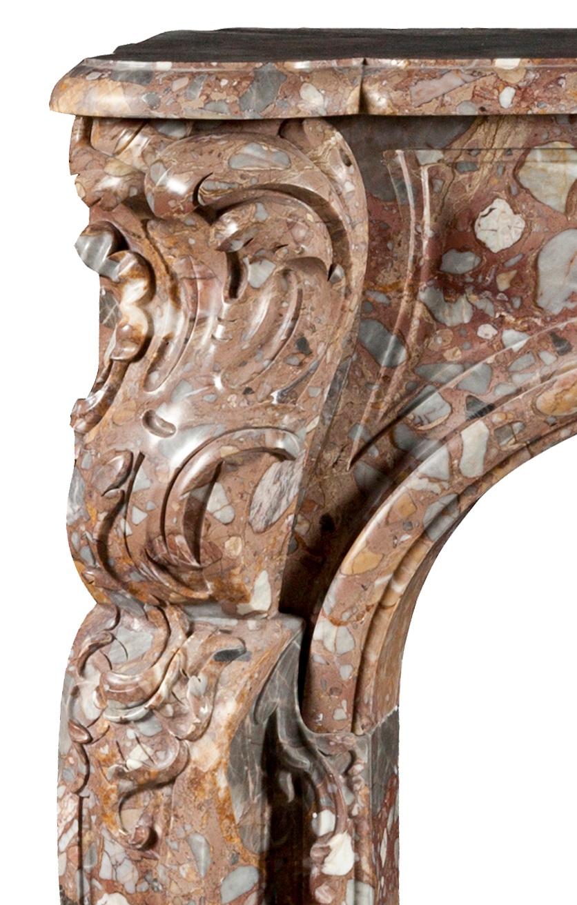 Reproduction d'un modèle Louis XV français du 18ème siècle  cheminée en marbre. La frise est ornée en son centre d'un cartouche sculpté, entouré de fleurs. Les jambages moulurés et façonnés sont surmontés d'embouts à volutes.